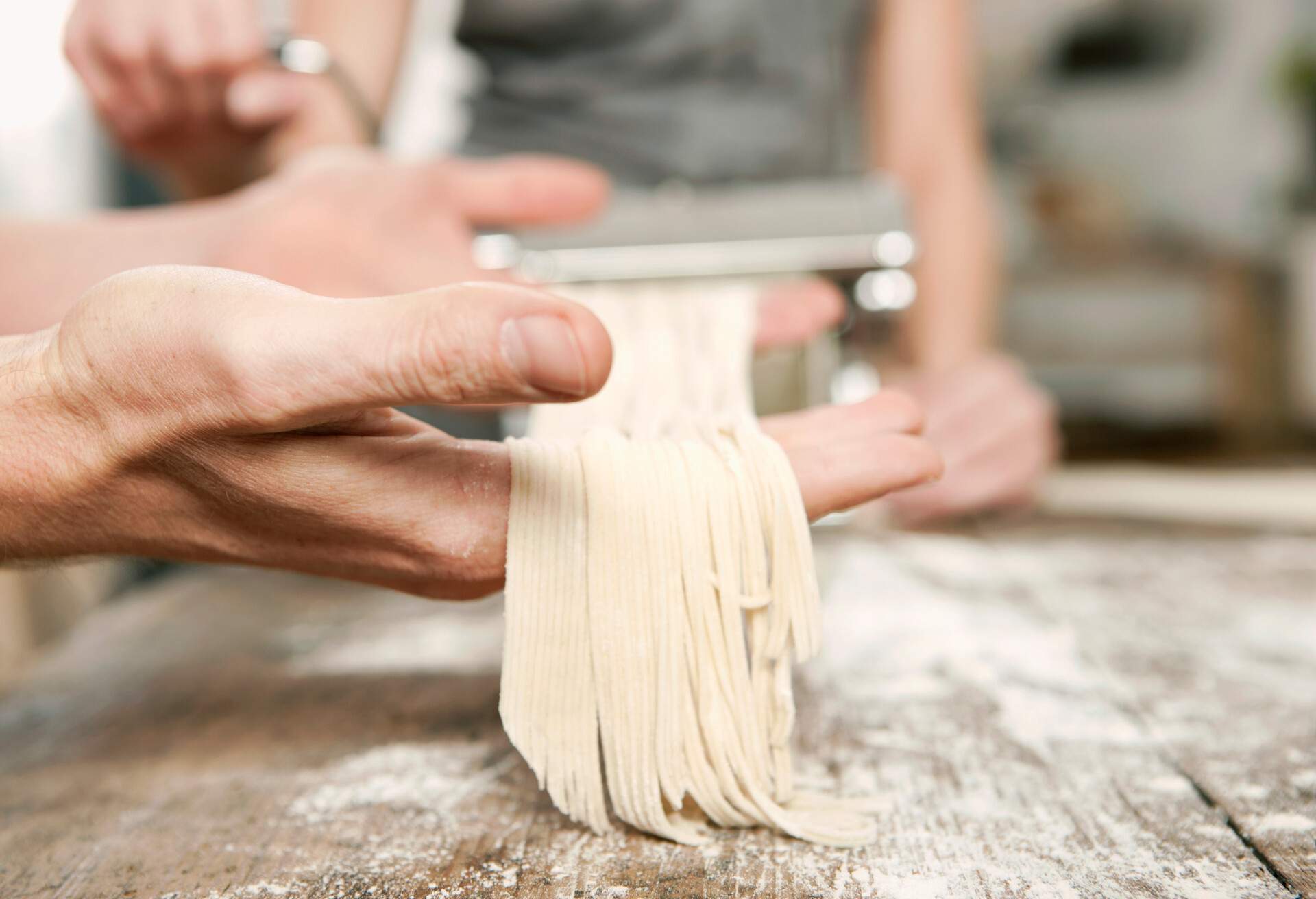 A hand holding freshly cut pasta noodles.