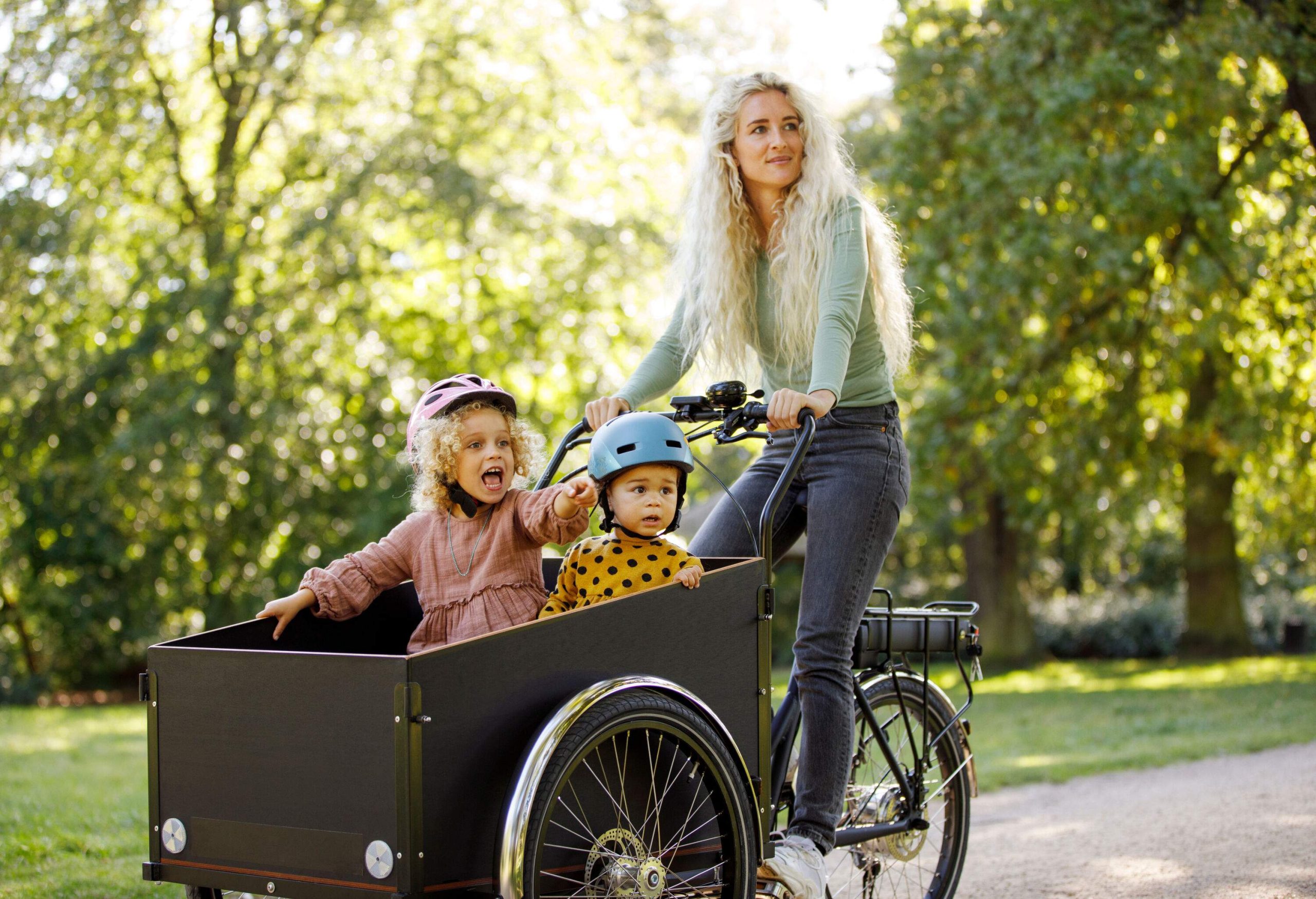A mother and her two children riding on a modern cargo bike.