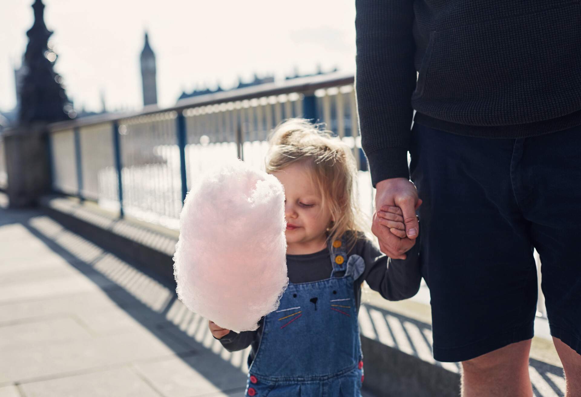 Little toddler girl eating Candy floss by the River Thames