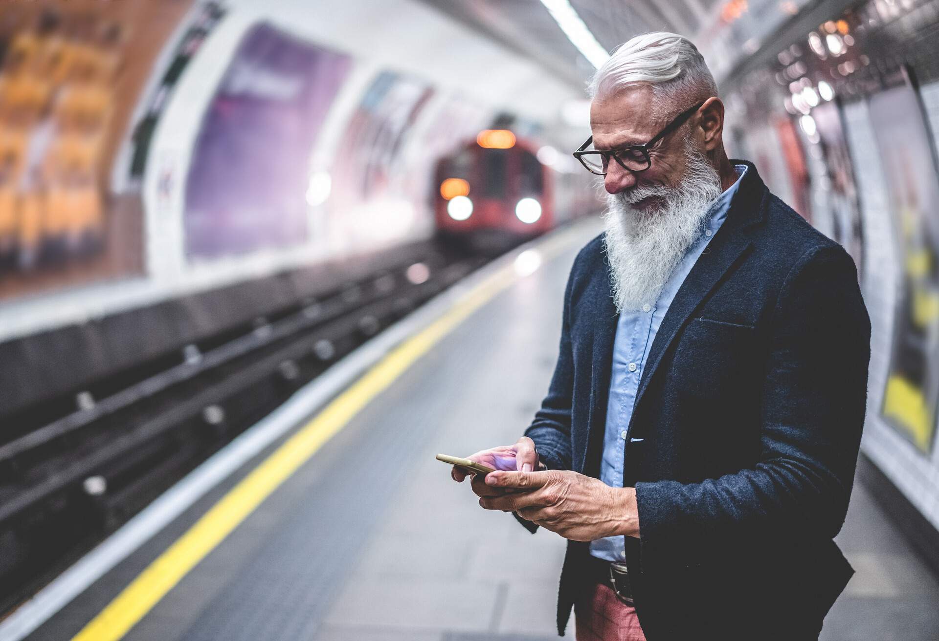Senior hipster man using smartphone in subway underground.