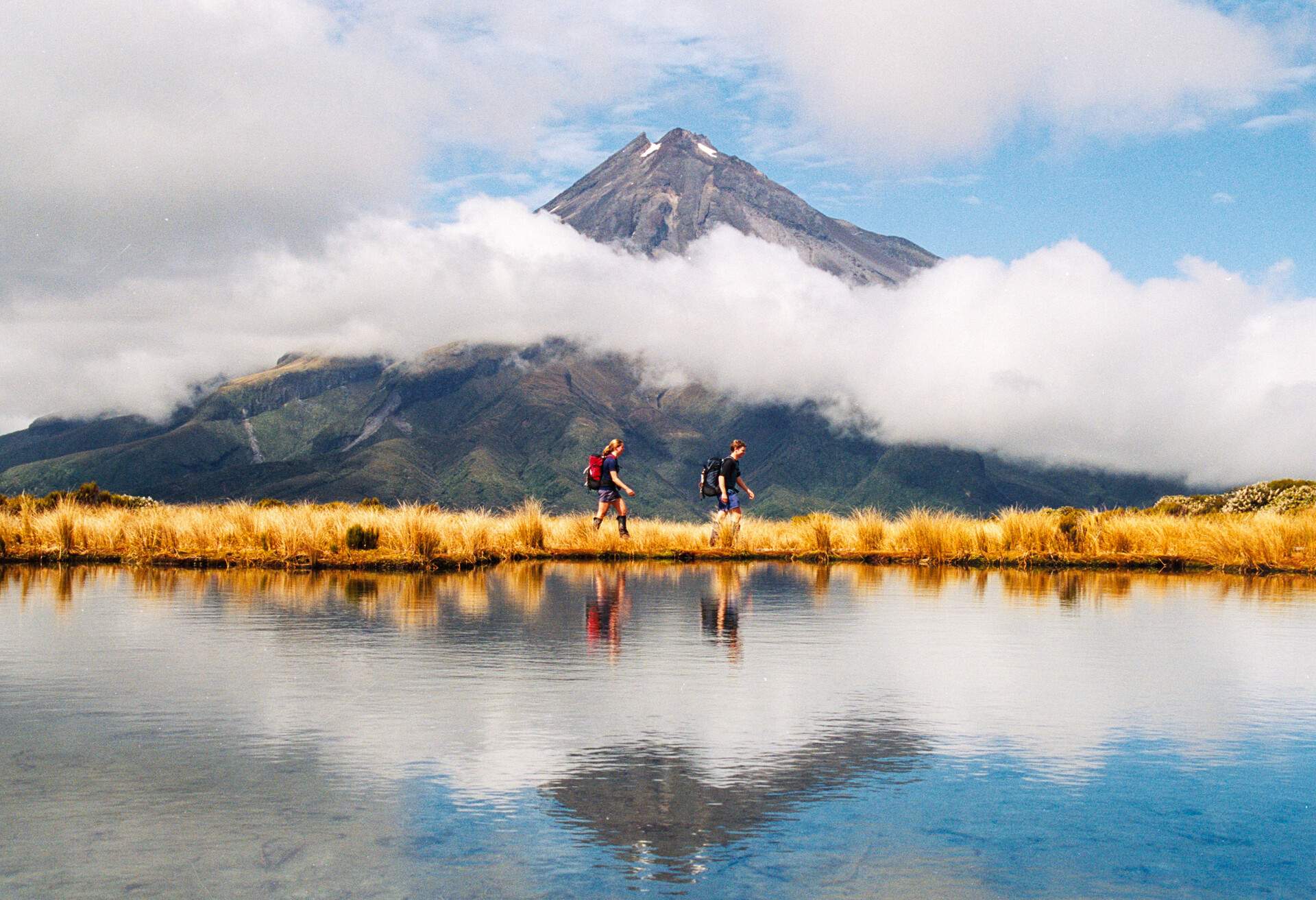 Hiker couple Reflection of Mount Taranaki Egmont in natural lake
