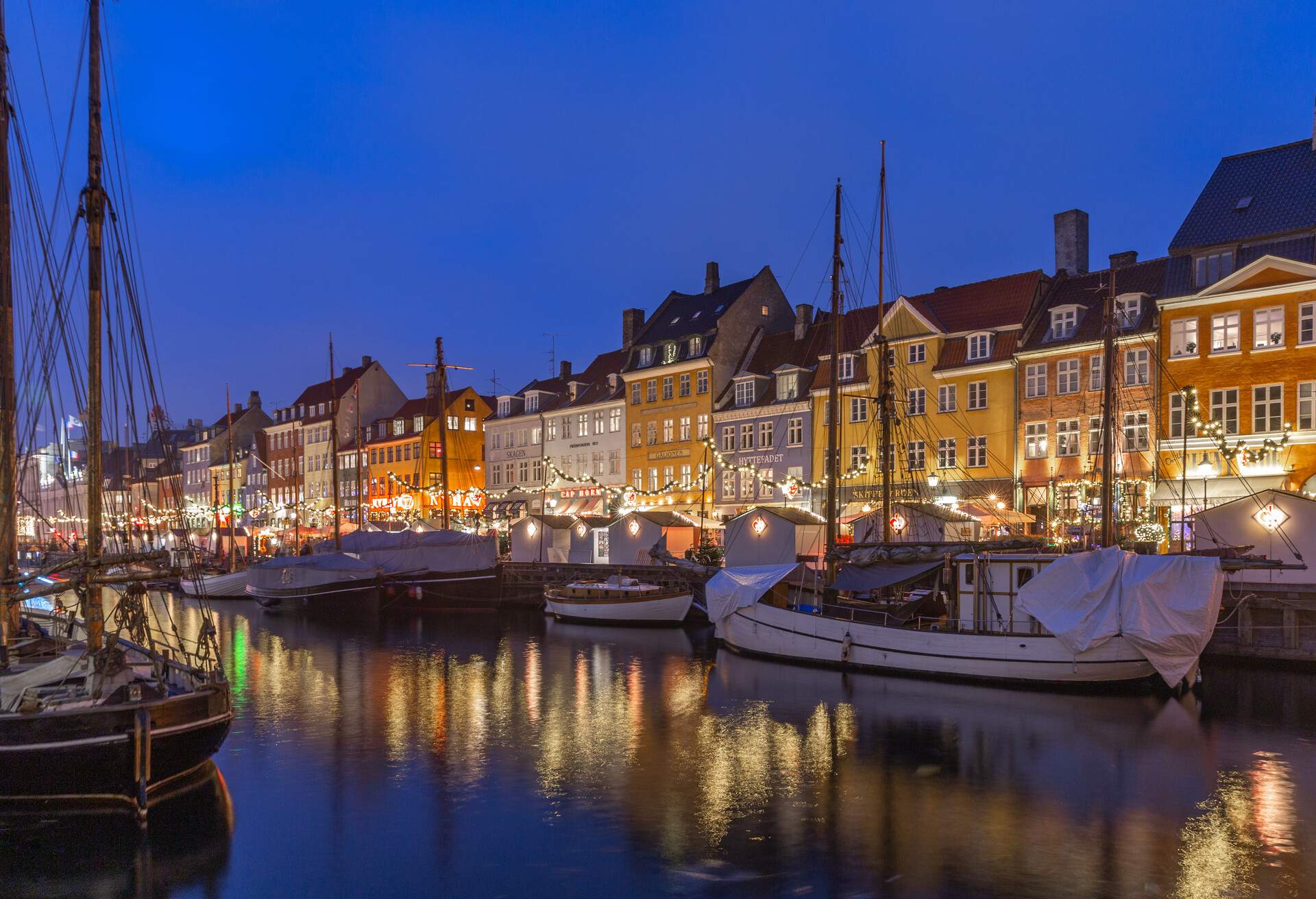 Colourful buildings along the harbour with boats wrapped in white casings.