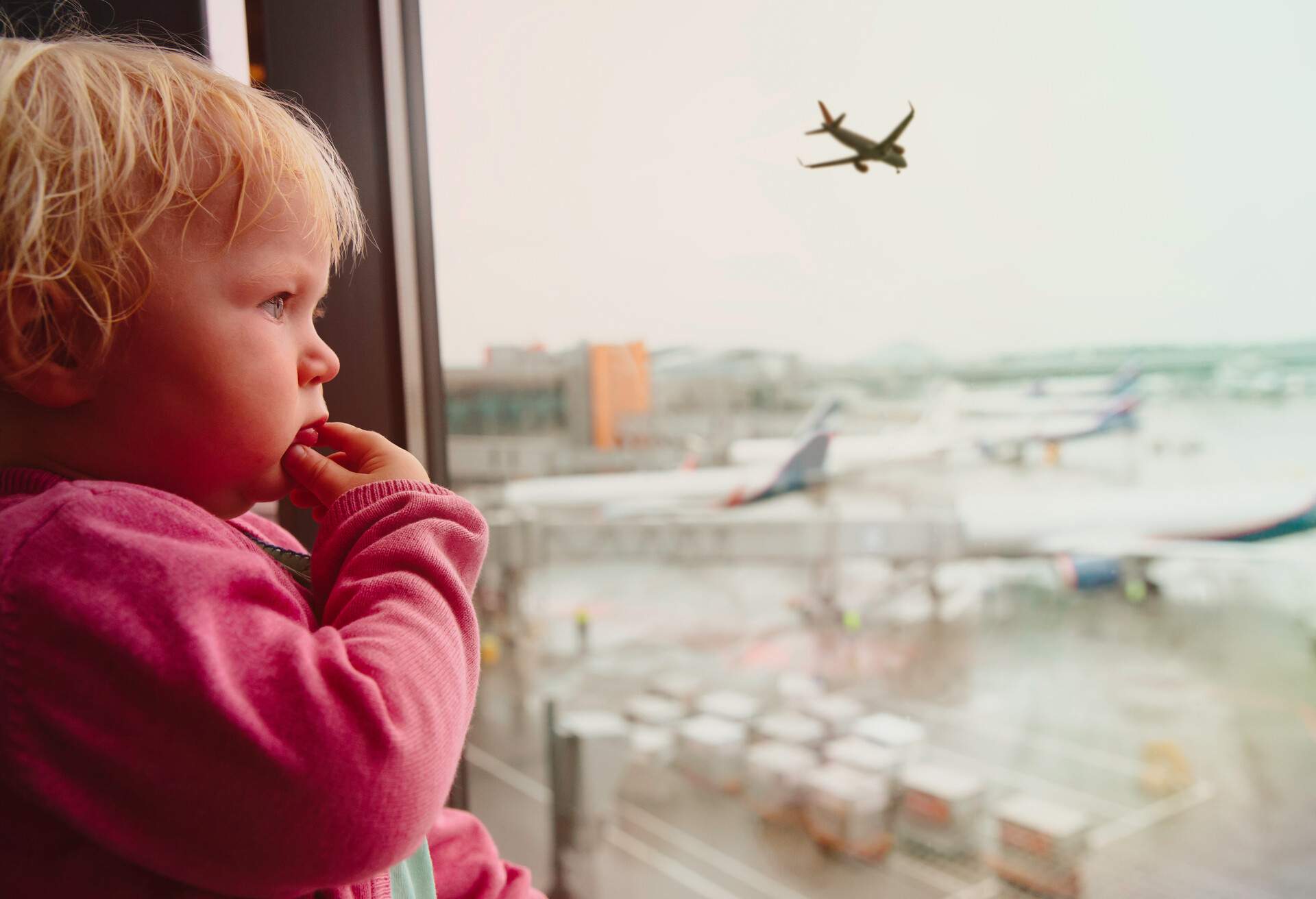 family travel concept- baby look at planes in airport