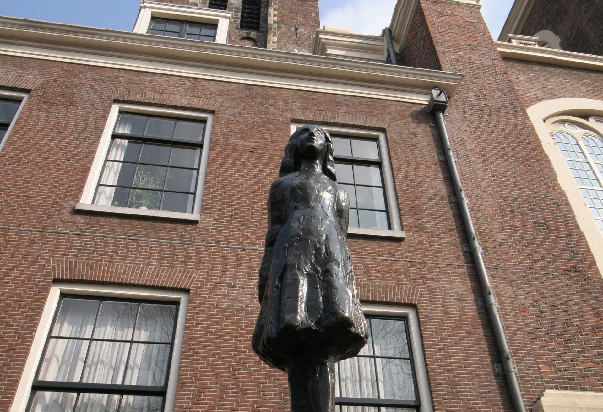The statue of Anne Frank is displayed in front of the Anne Frank House building in Amsterdam, Netherlands.