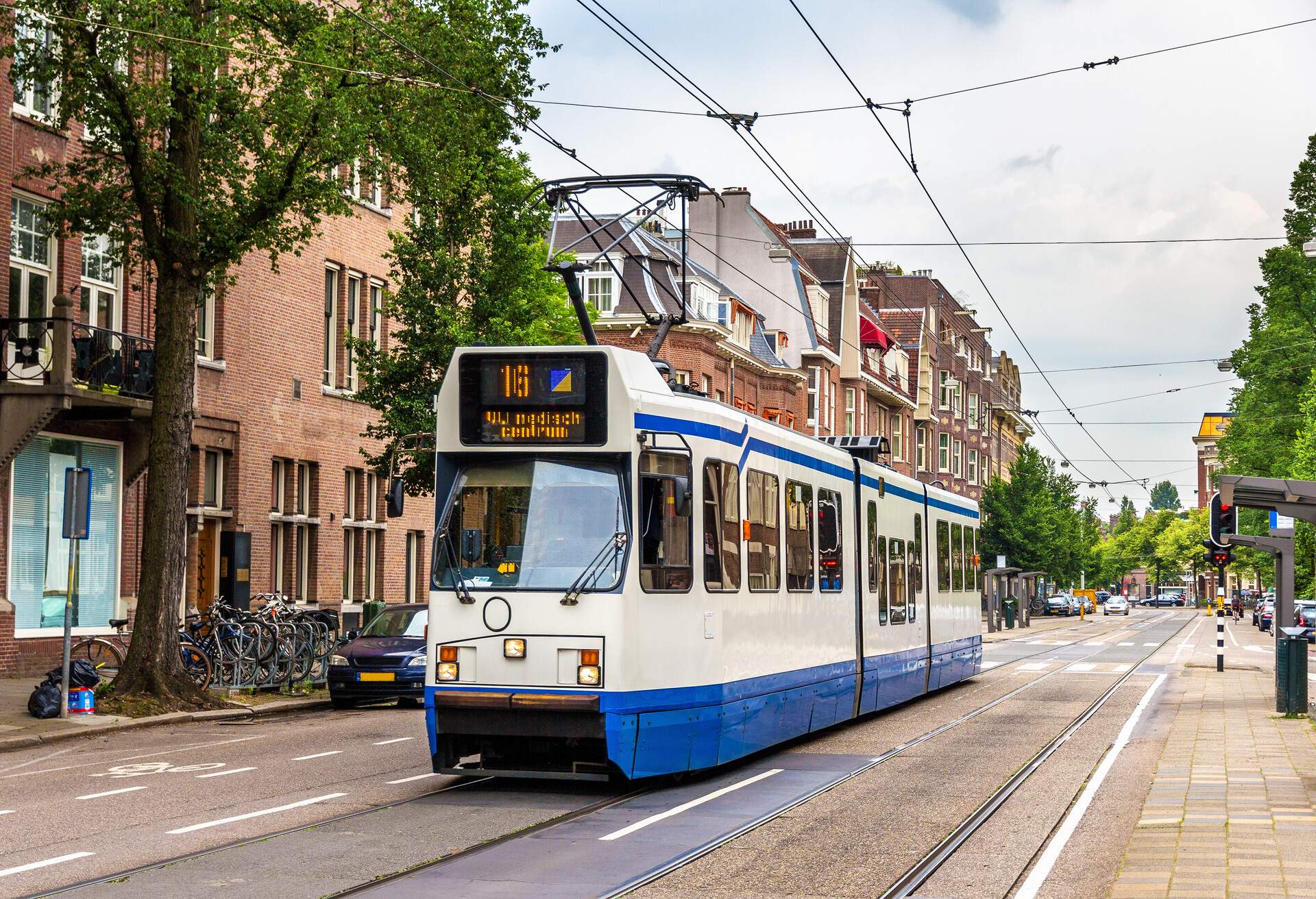 A tram passing through a city with redbrick buildings.