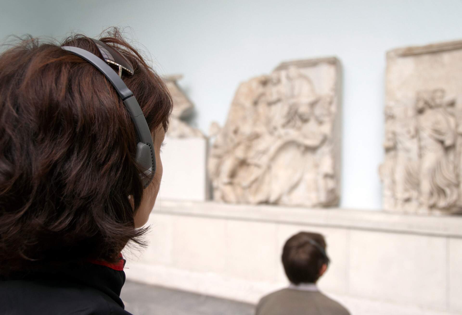 People wearing headphones are looking at stone carvings in a museum.