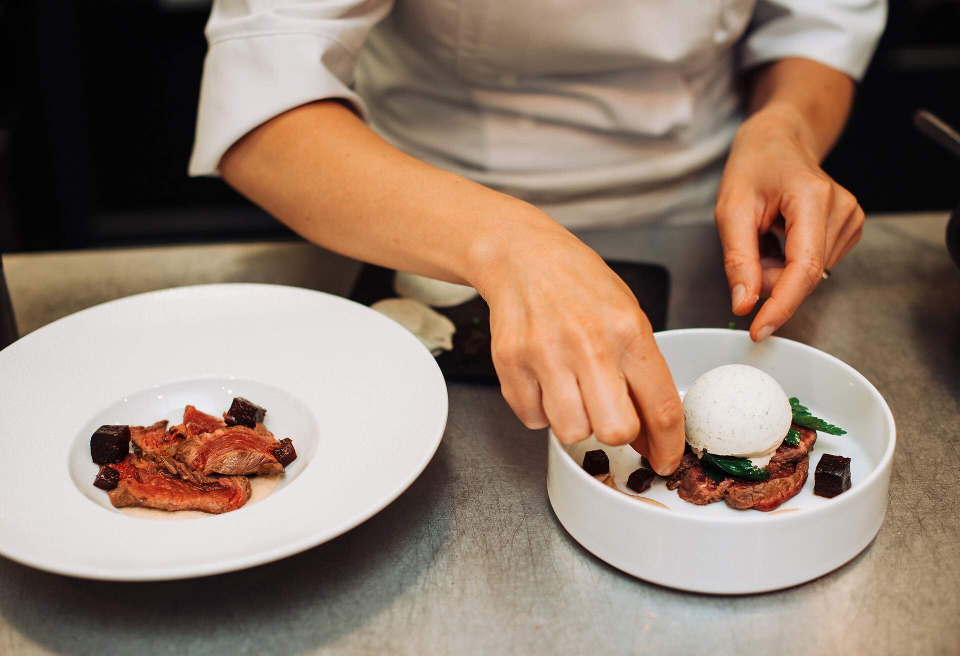 Chef hands preparing a gourmet dish in a white plate.