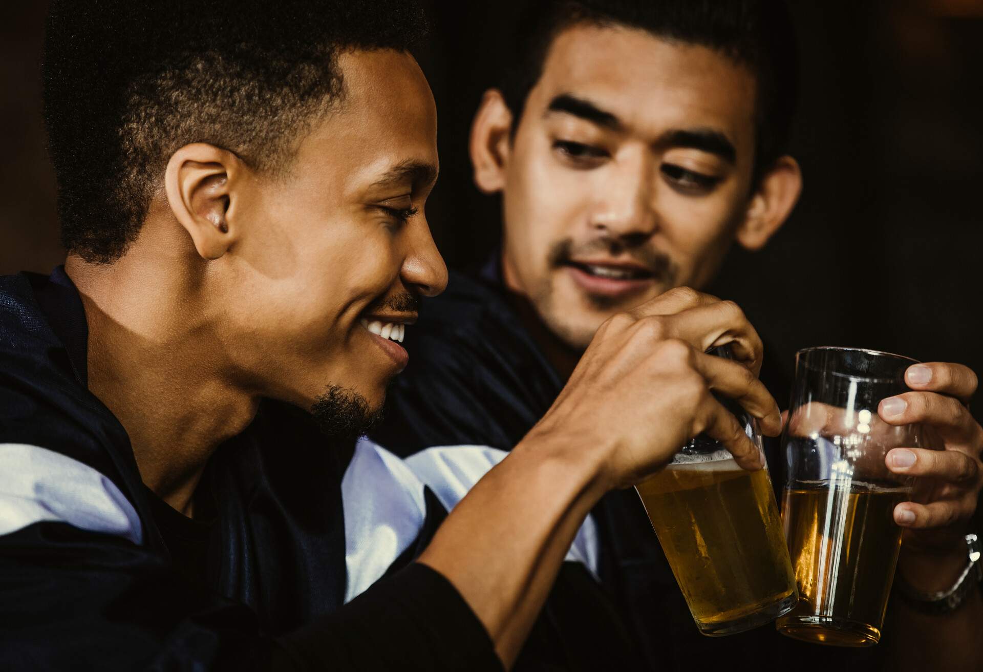 Two men make a toast with beer glasses.