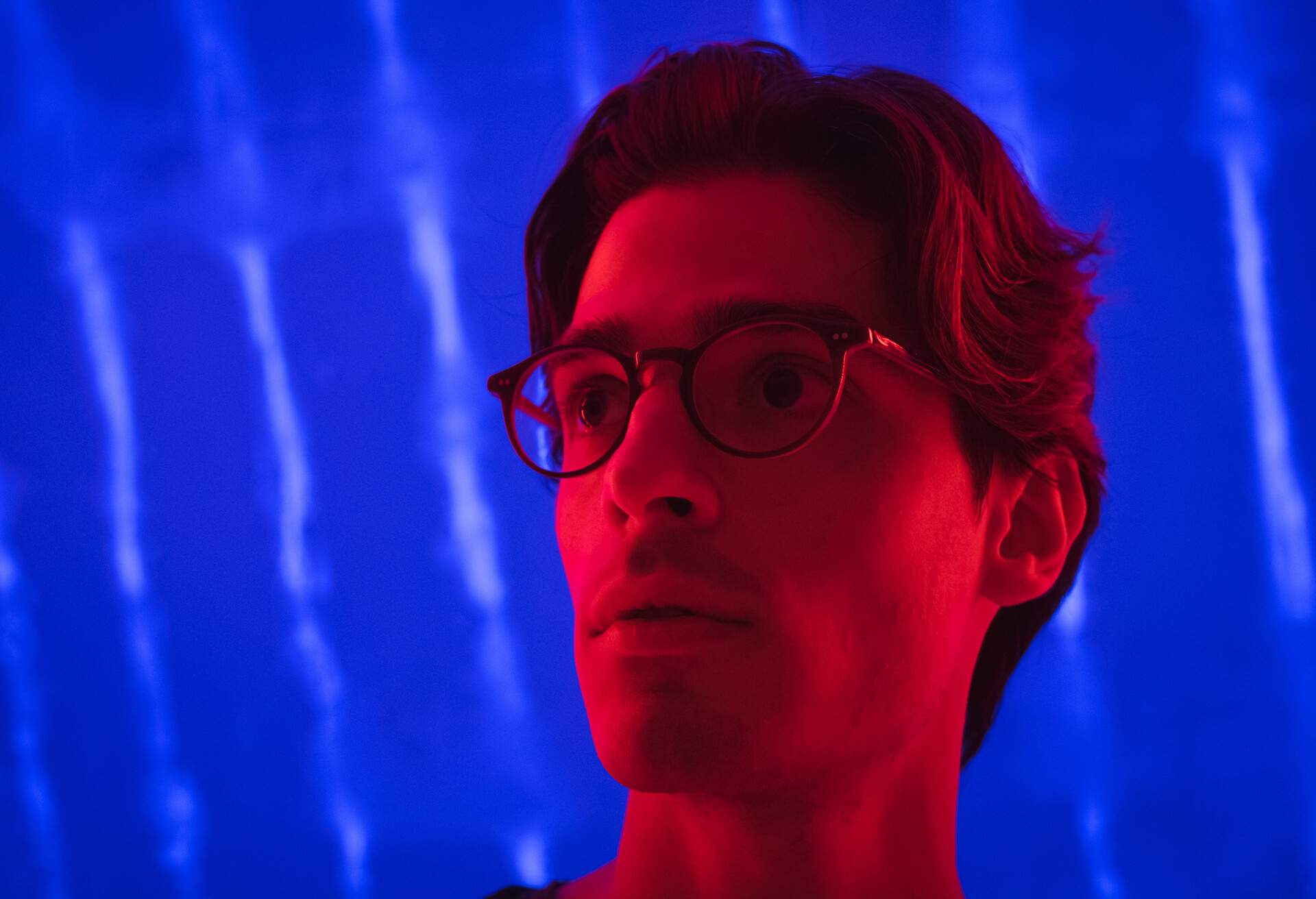 A face of a man in red light with blue background.