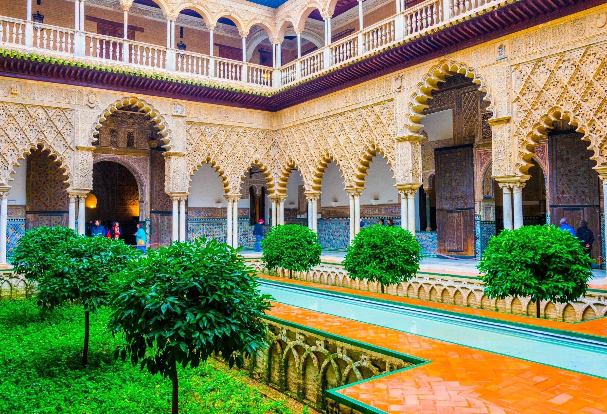 A fascinating Courtyard of the Maidens at Royal Alcazars with a long pool alongside an intricate patio.