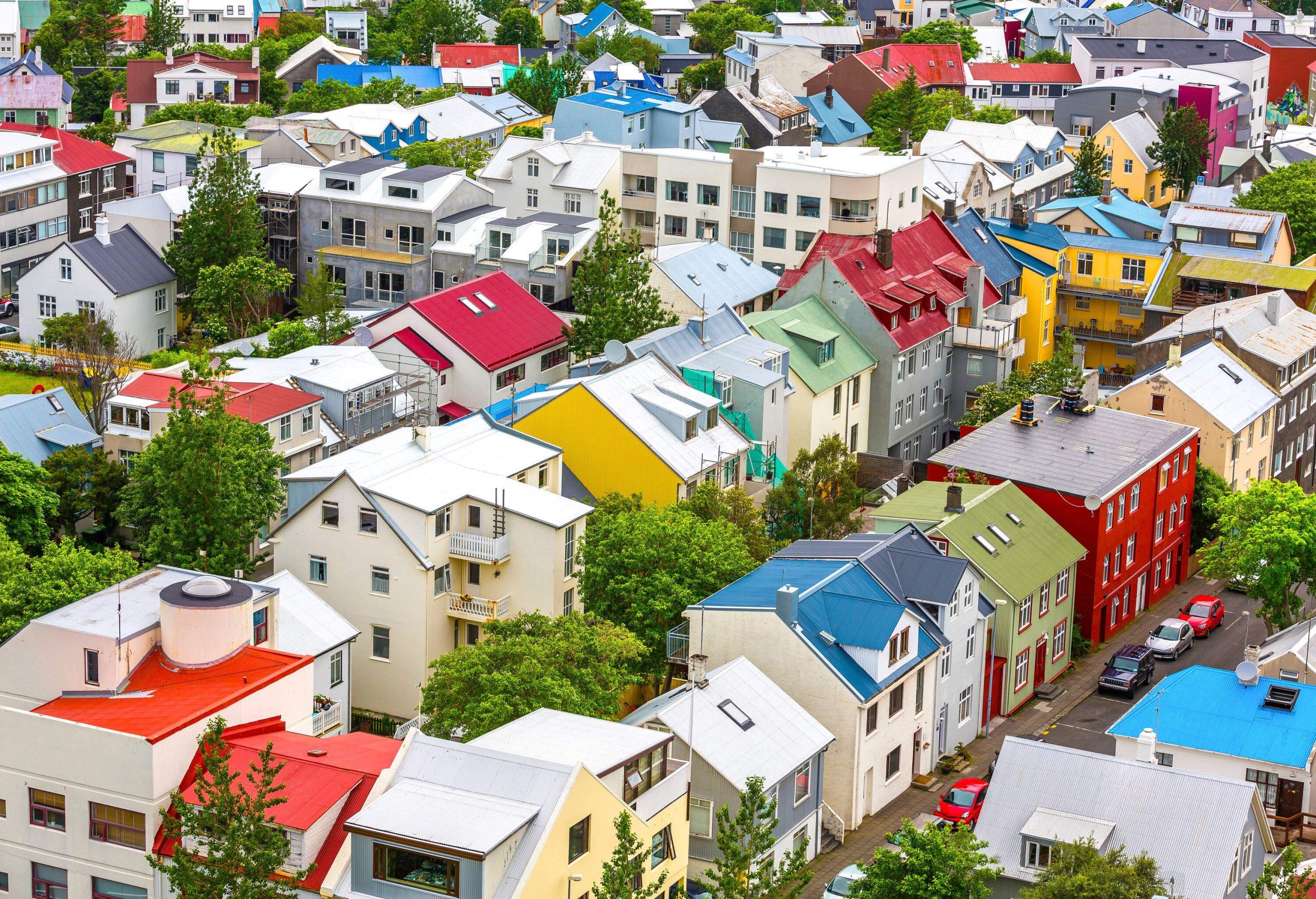 A city block filled with colourful houses and buildings, with cars parked on the street.