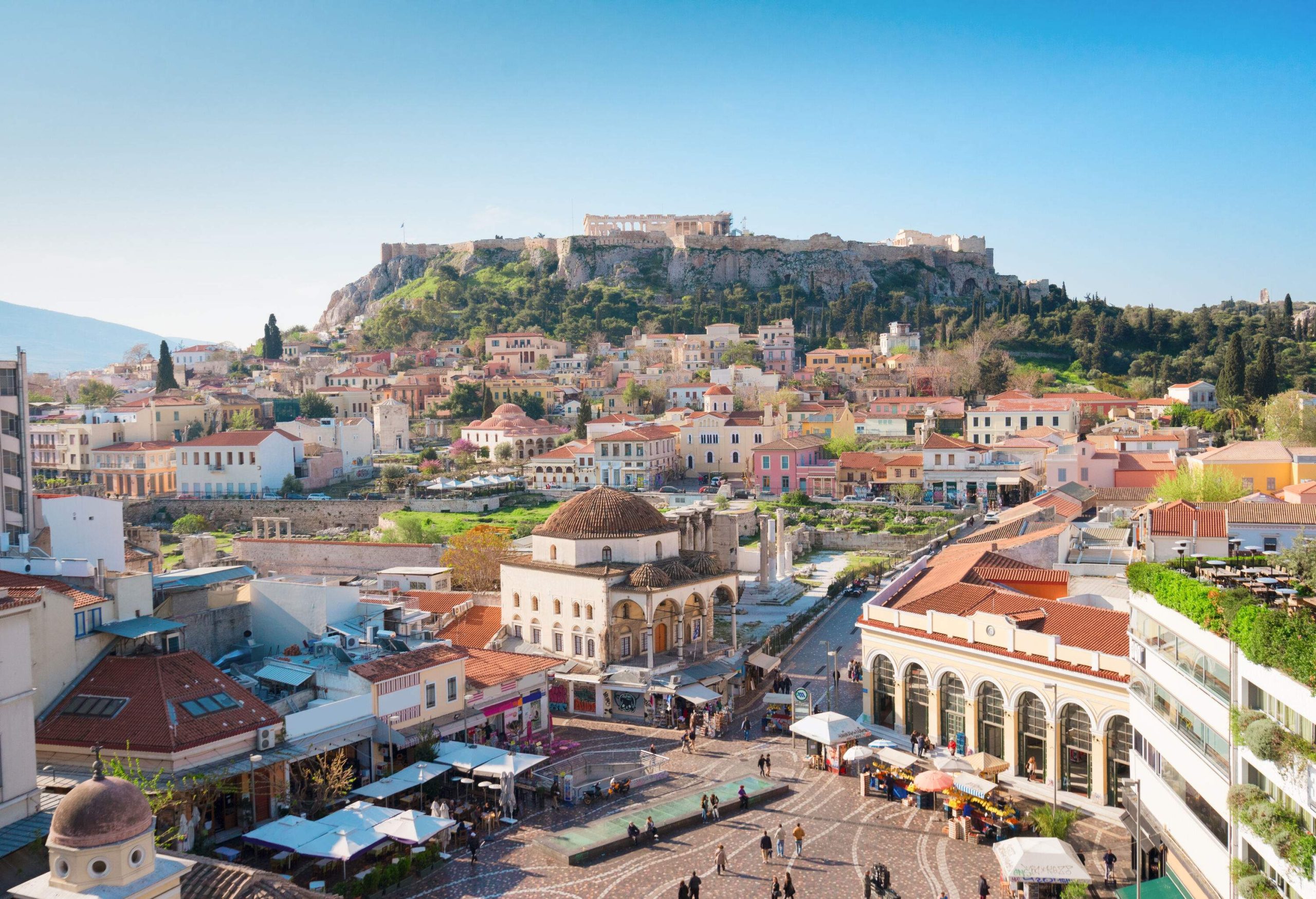 A cityscape with a market square in the middle and the Acropolis in the background.
