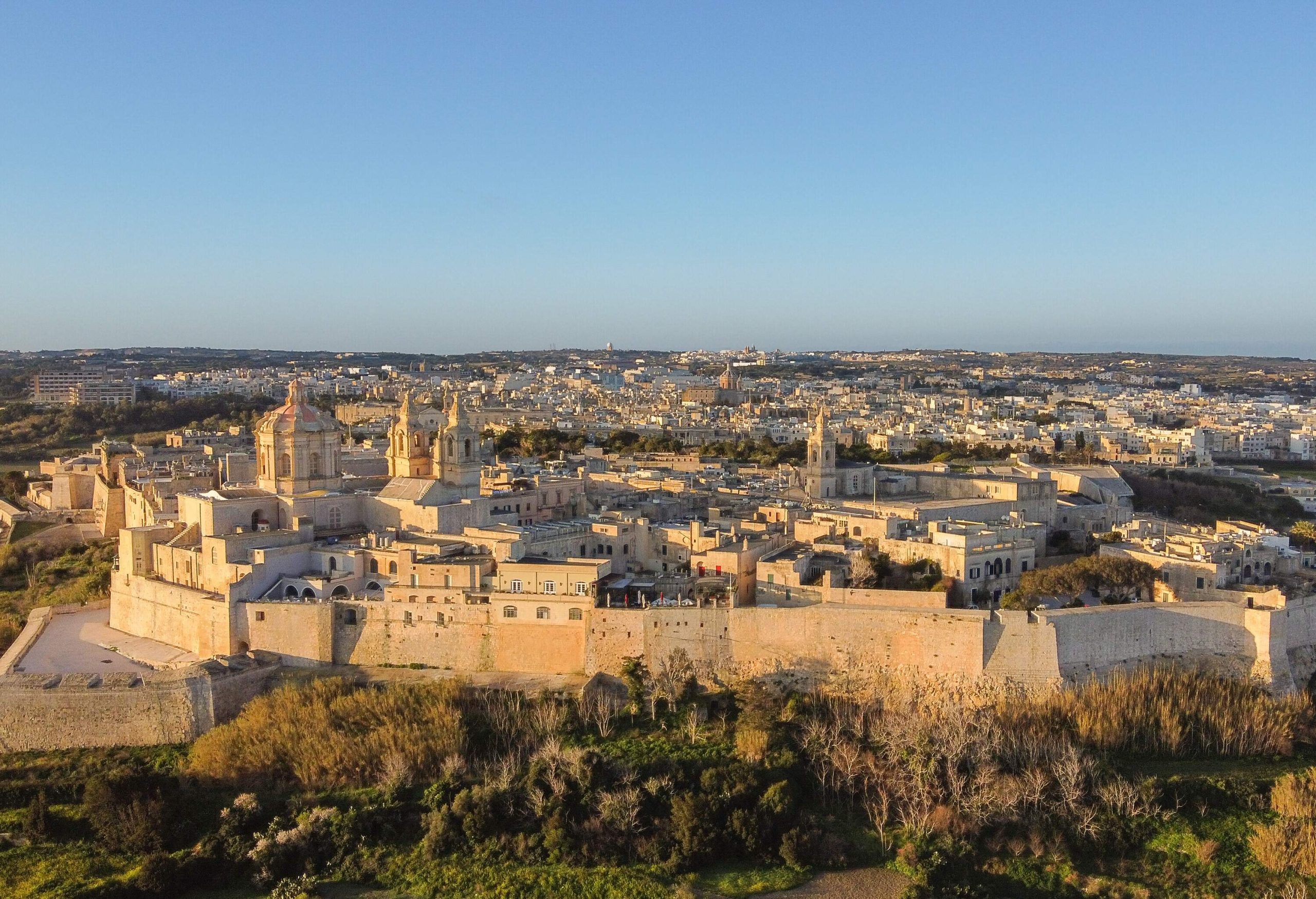 An ancient walled-in city under a cloudless morning sky.