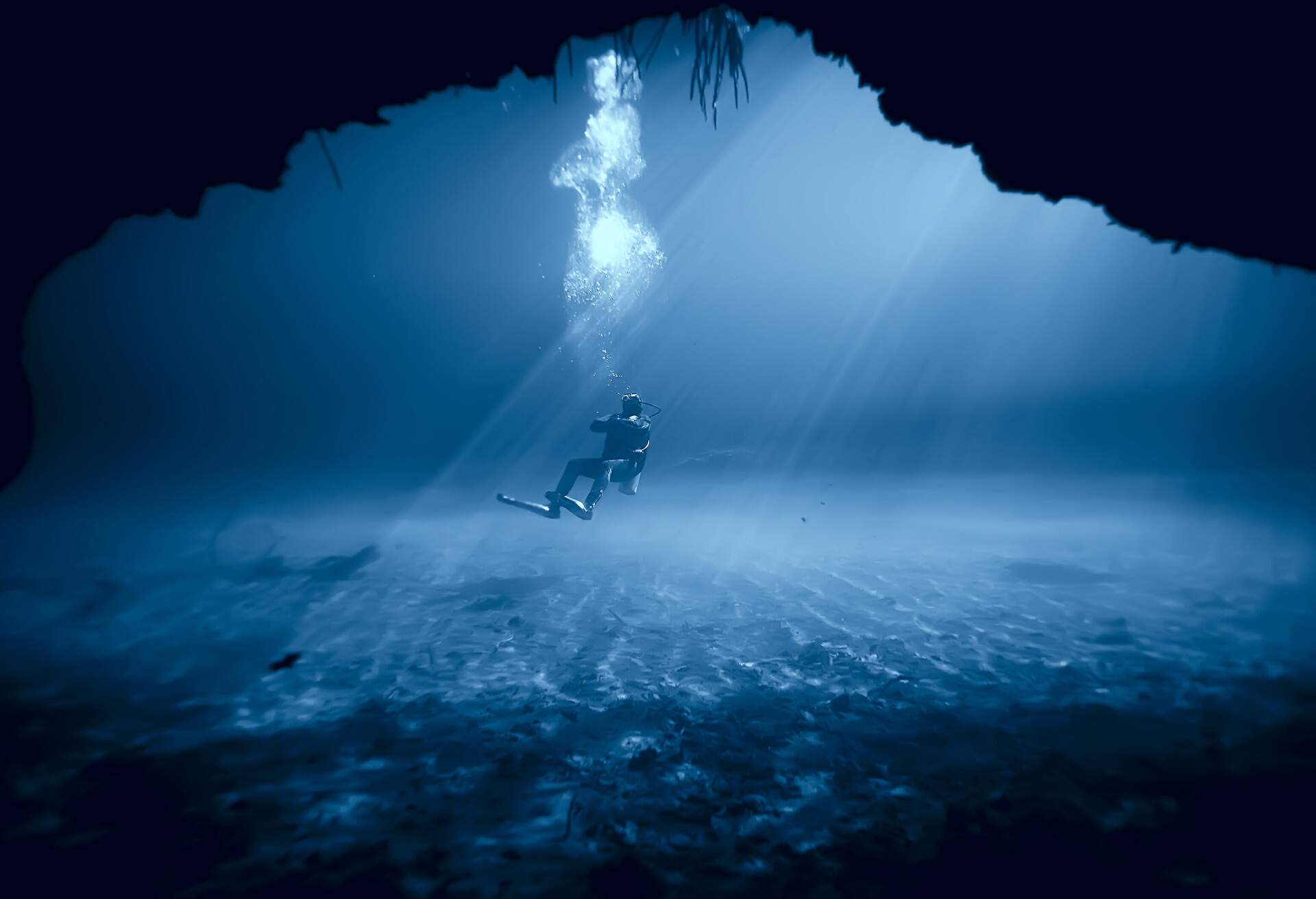 A diver breathes out bubbles under deep blue waters.