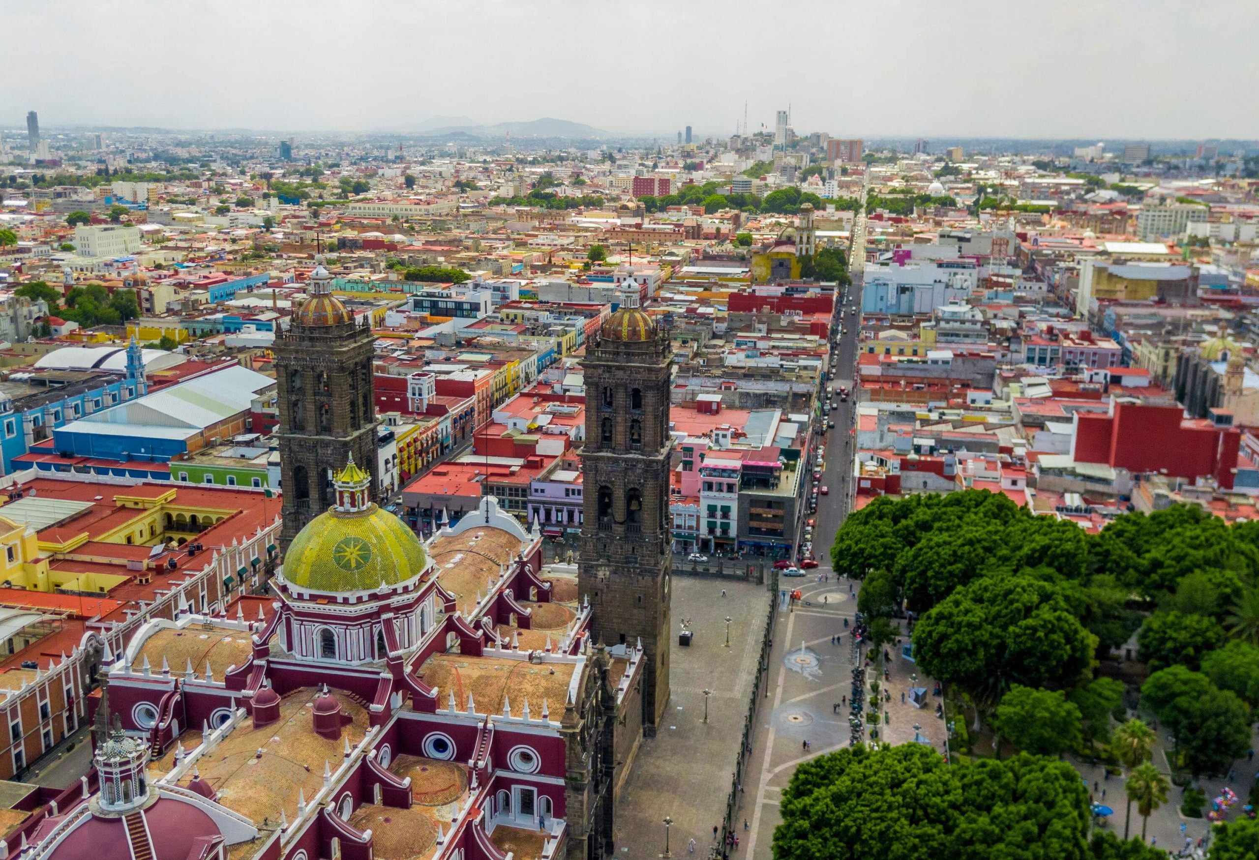 A dome church with twin towers overlooking a green park and the urban landscape of a city.