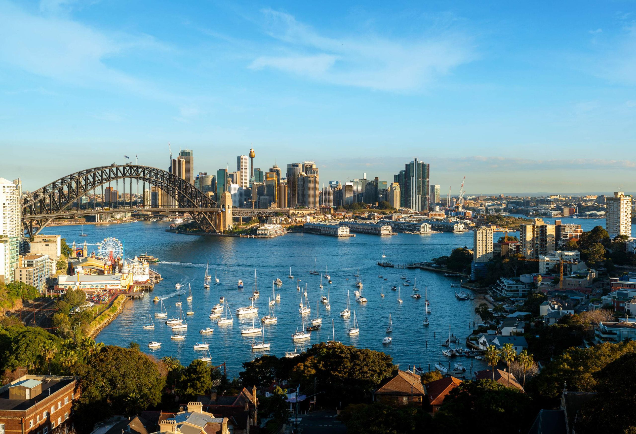 Sailboats dotting the bay, with the Sydney Harbour Bridge in the background.