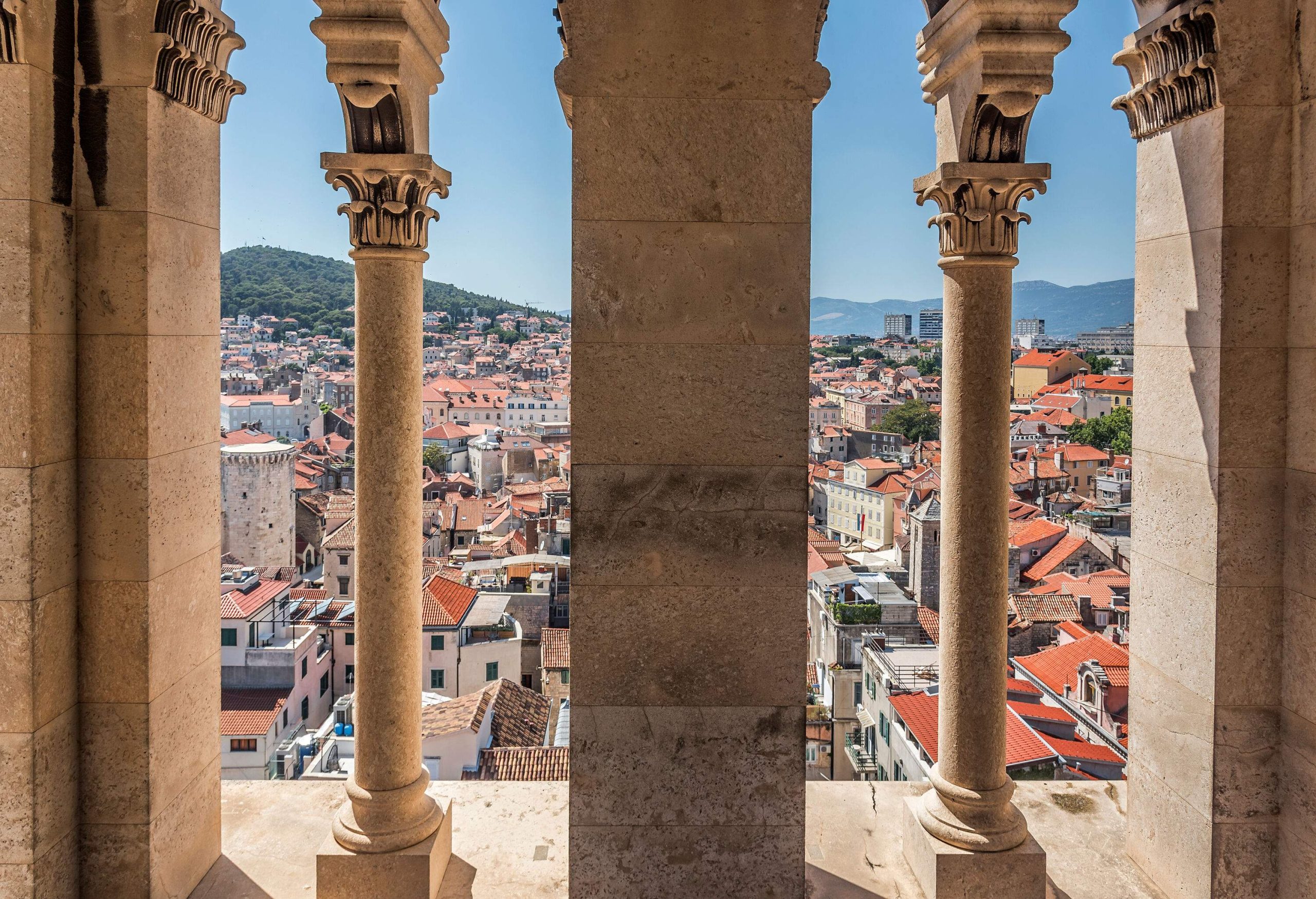 An old town dominated by classic buildings with red brick roofs seen from the window of an ancient tower.