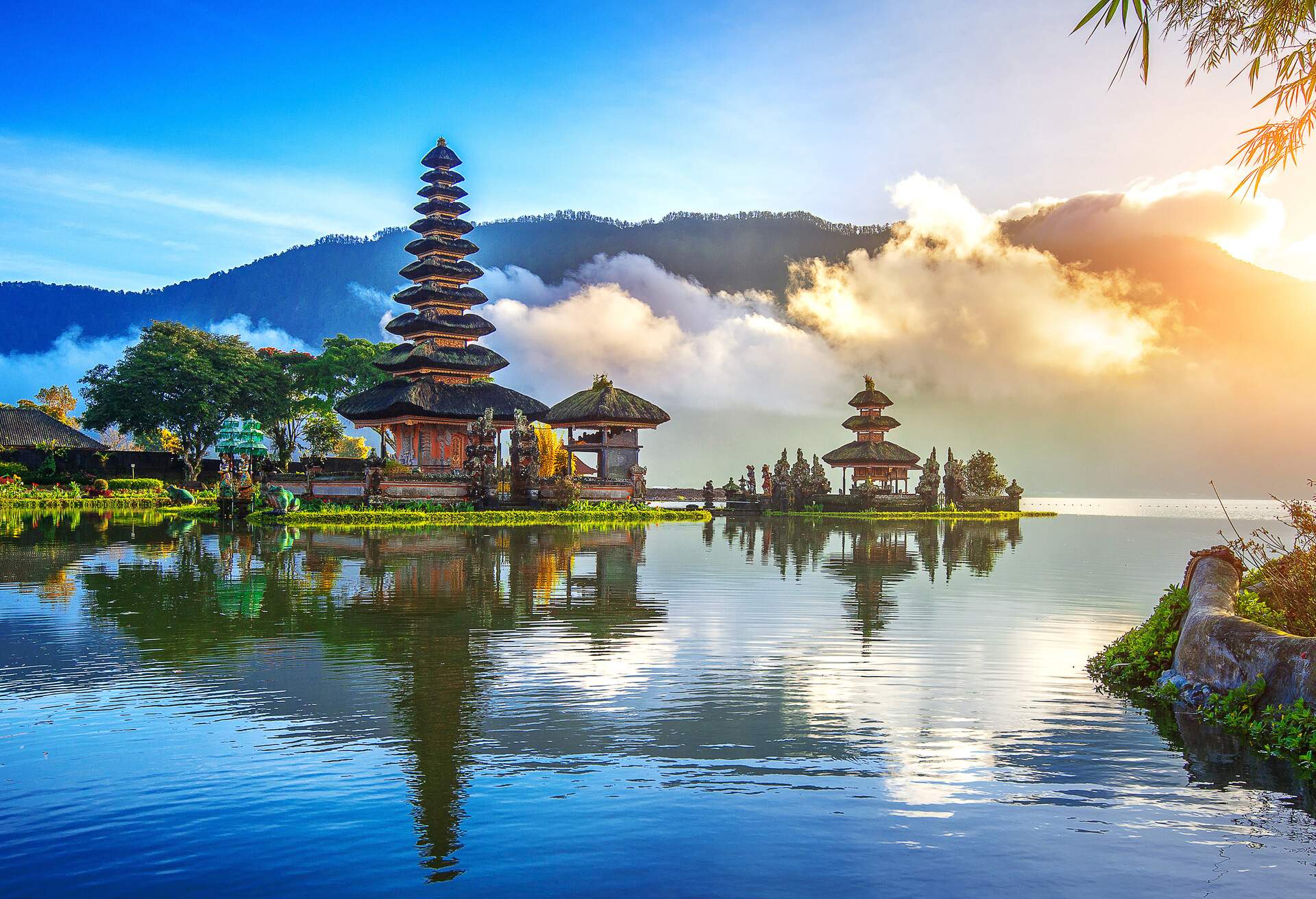 A captivating village with temples towering over the lake water with foggy mountains in the background.