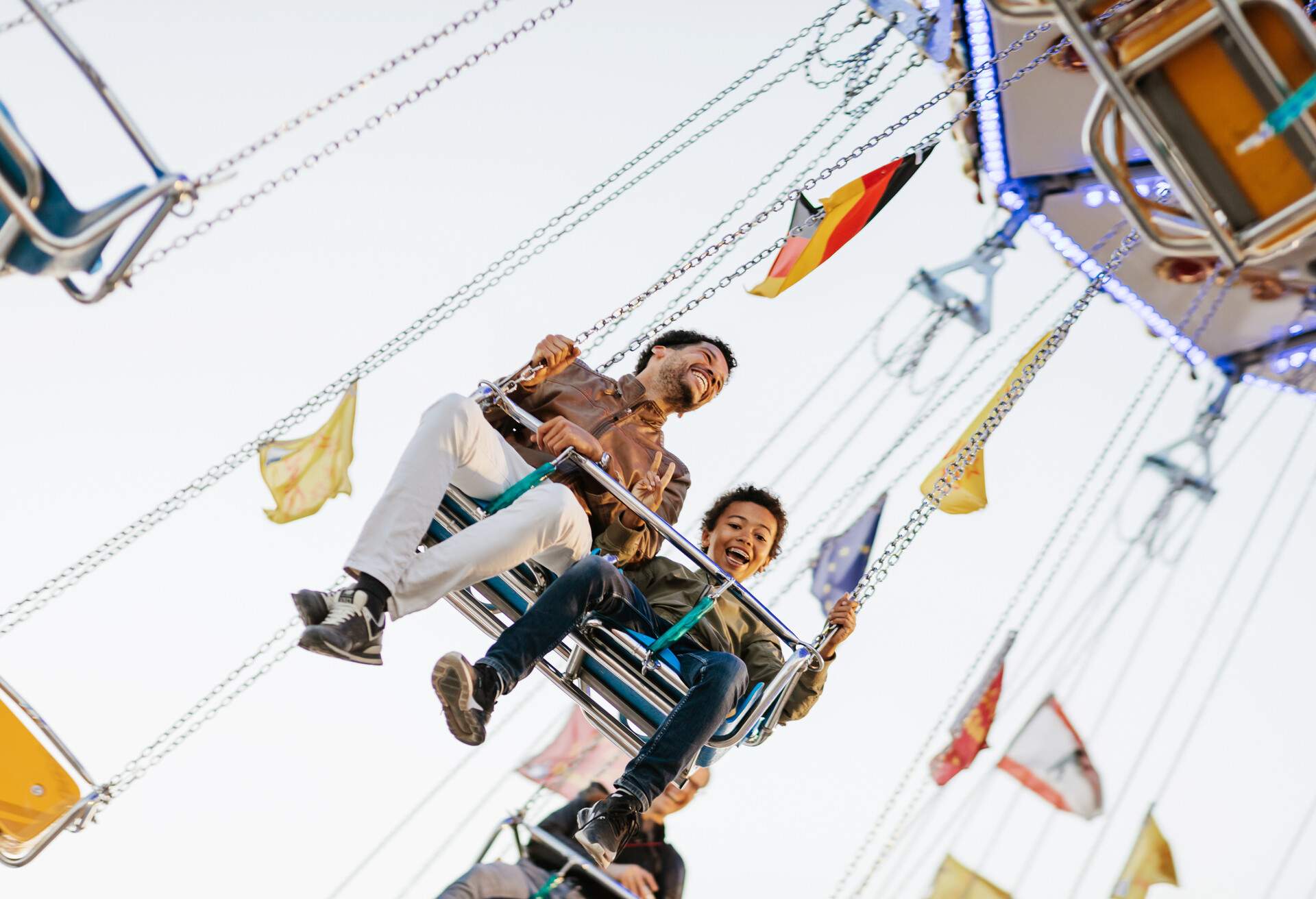 A happy father and son enjoying the large swing ride at the fun fair, creating cherished memories during their delightful day of amusement and joy.