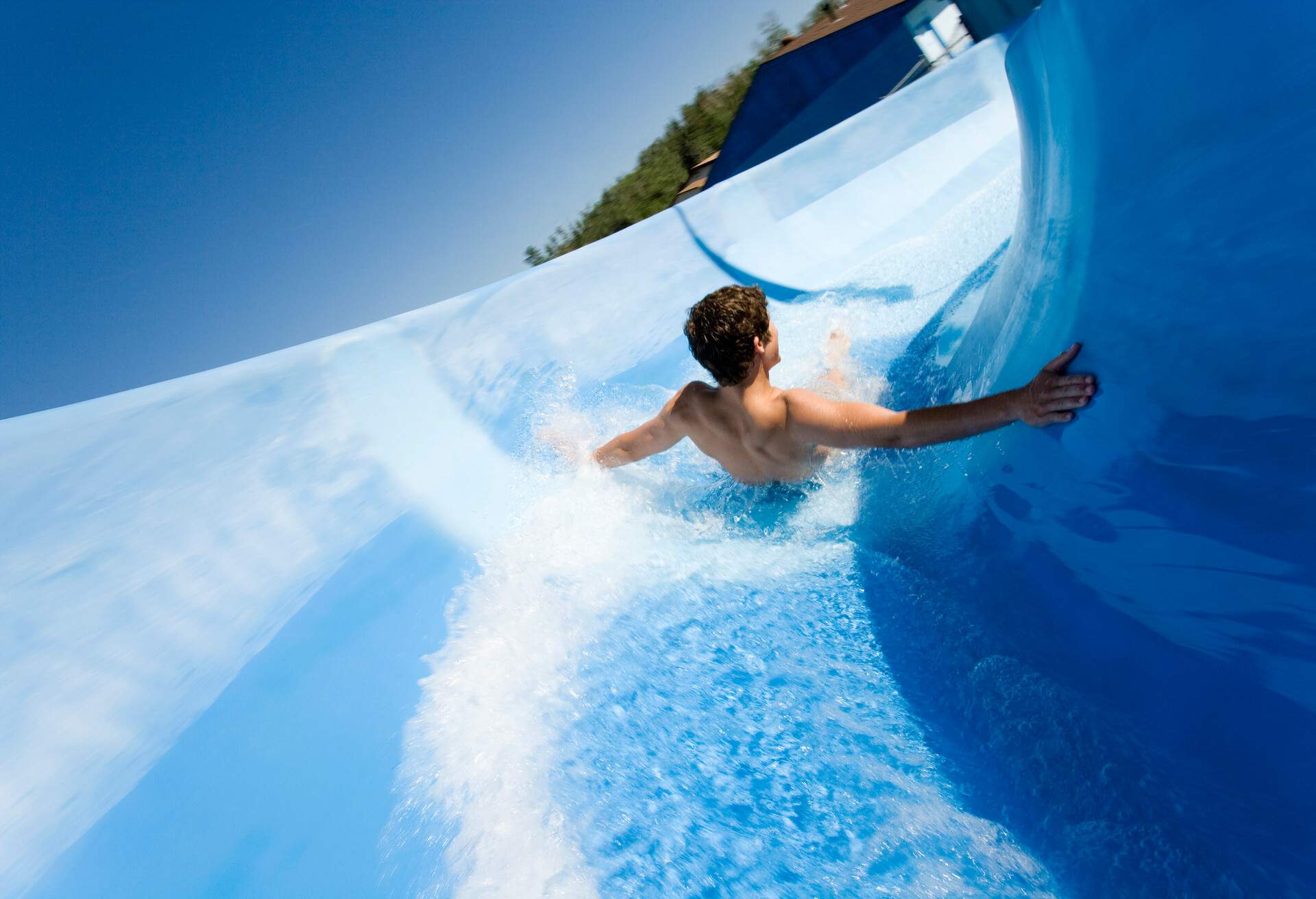 A man goes down a blue water slide.