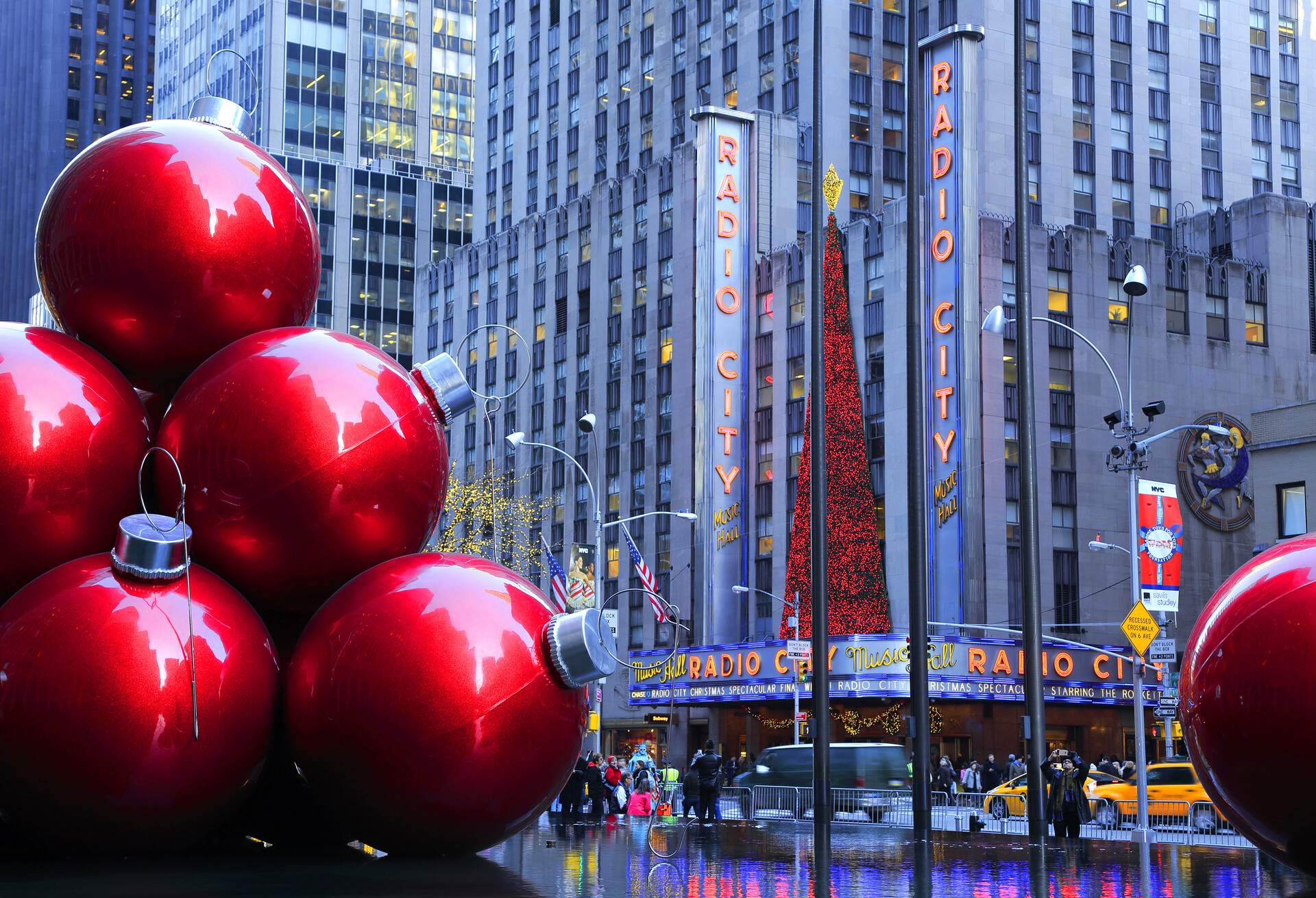 A huge display of red ornamental Christmas balls on the pavement that offers a view of the city's buildings.