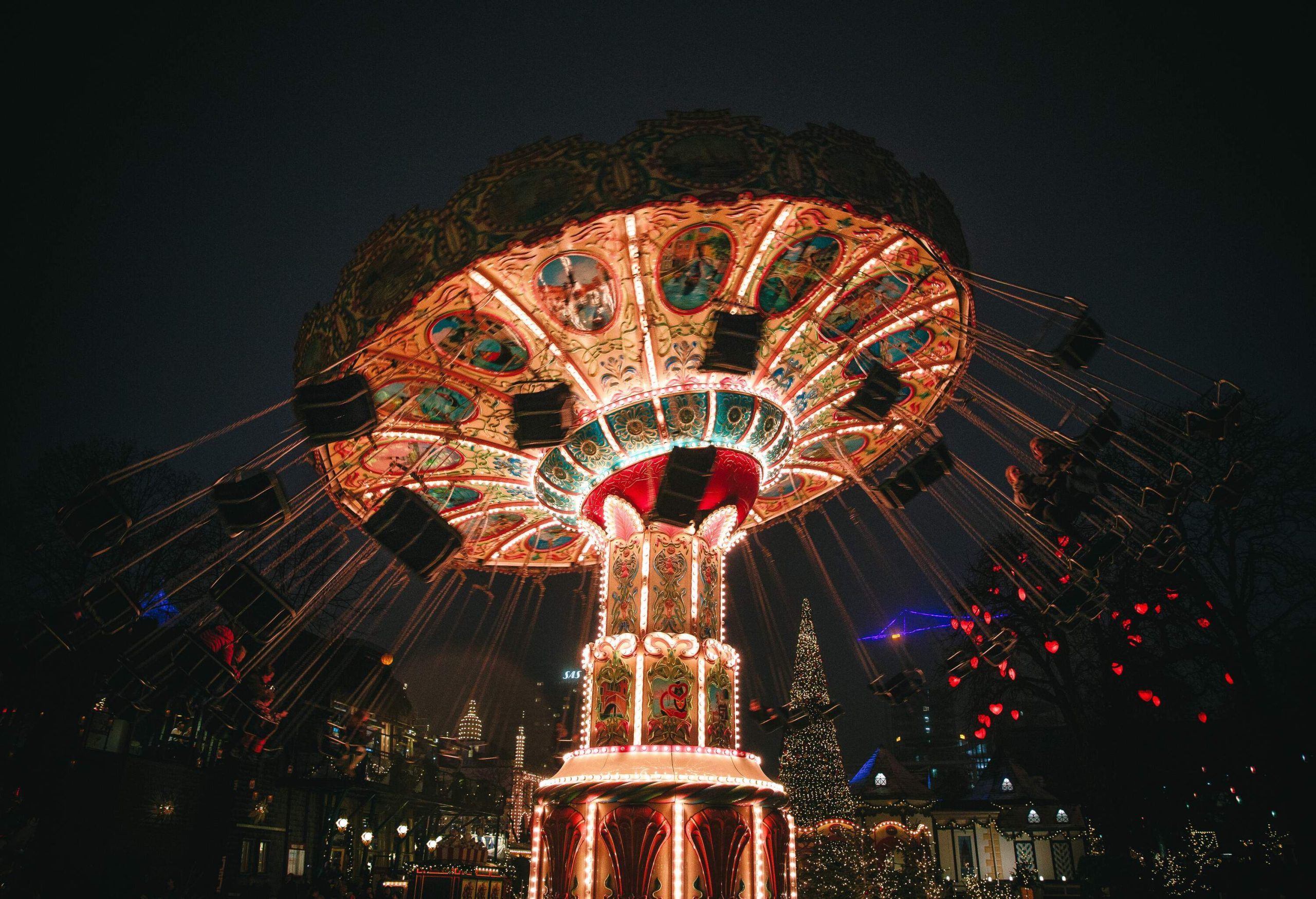 A night-time view of a bright and spinning swing carousel.
