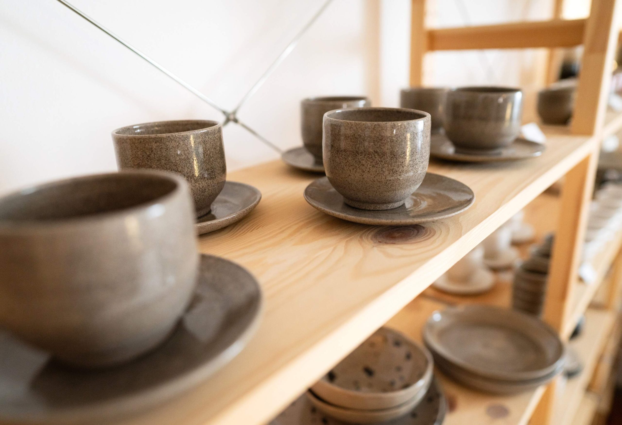 Close-up of sparkling ceramic cups and saucers on a wooden rack.