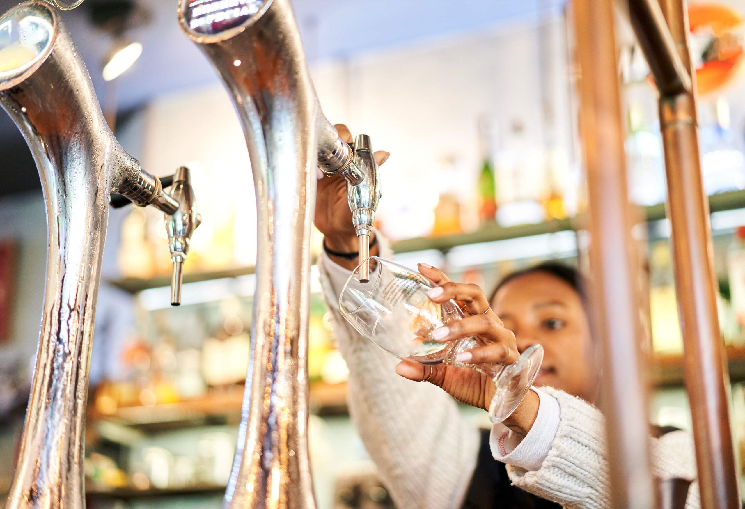 A young lady fills a glass on a beer tap.