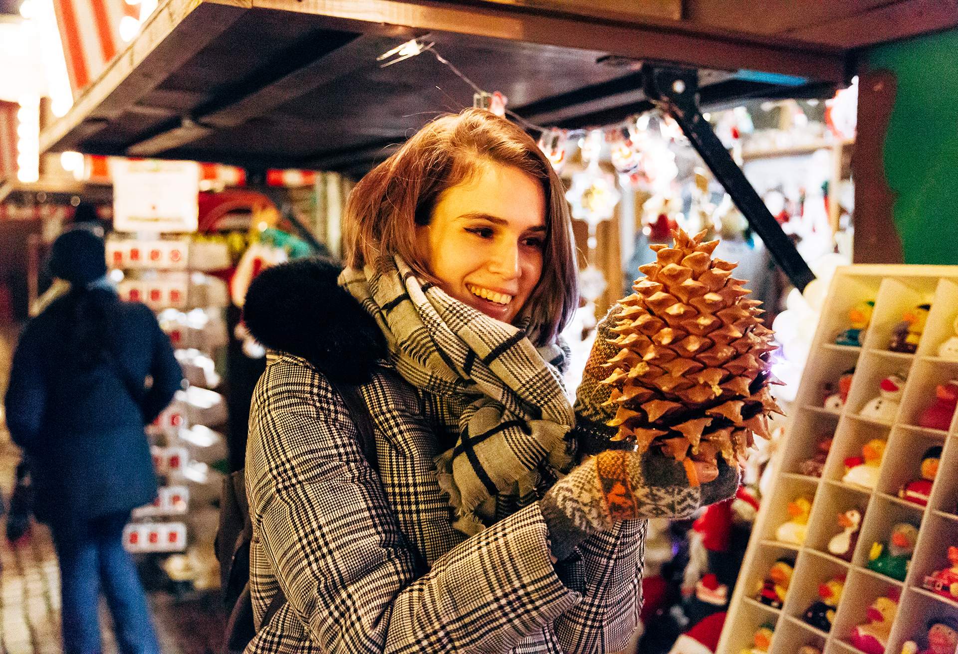 Close up of woman looking at a festive pine cone for sale at Christmas Market