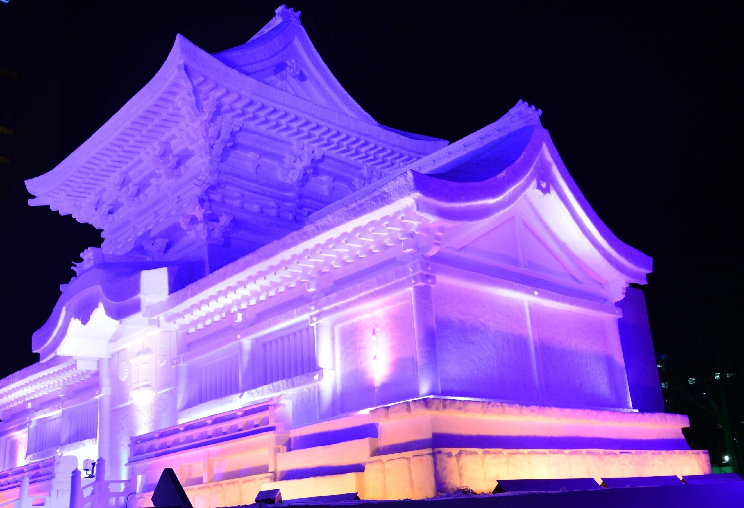 A brightly lit traditional Japanese building made of snow in purple light.