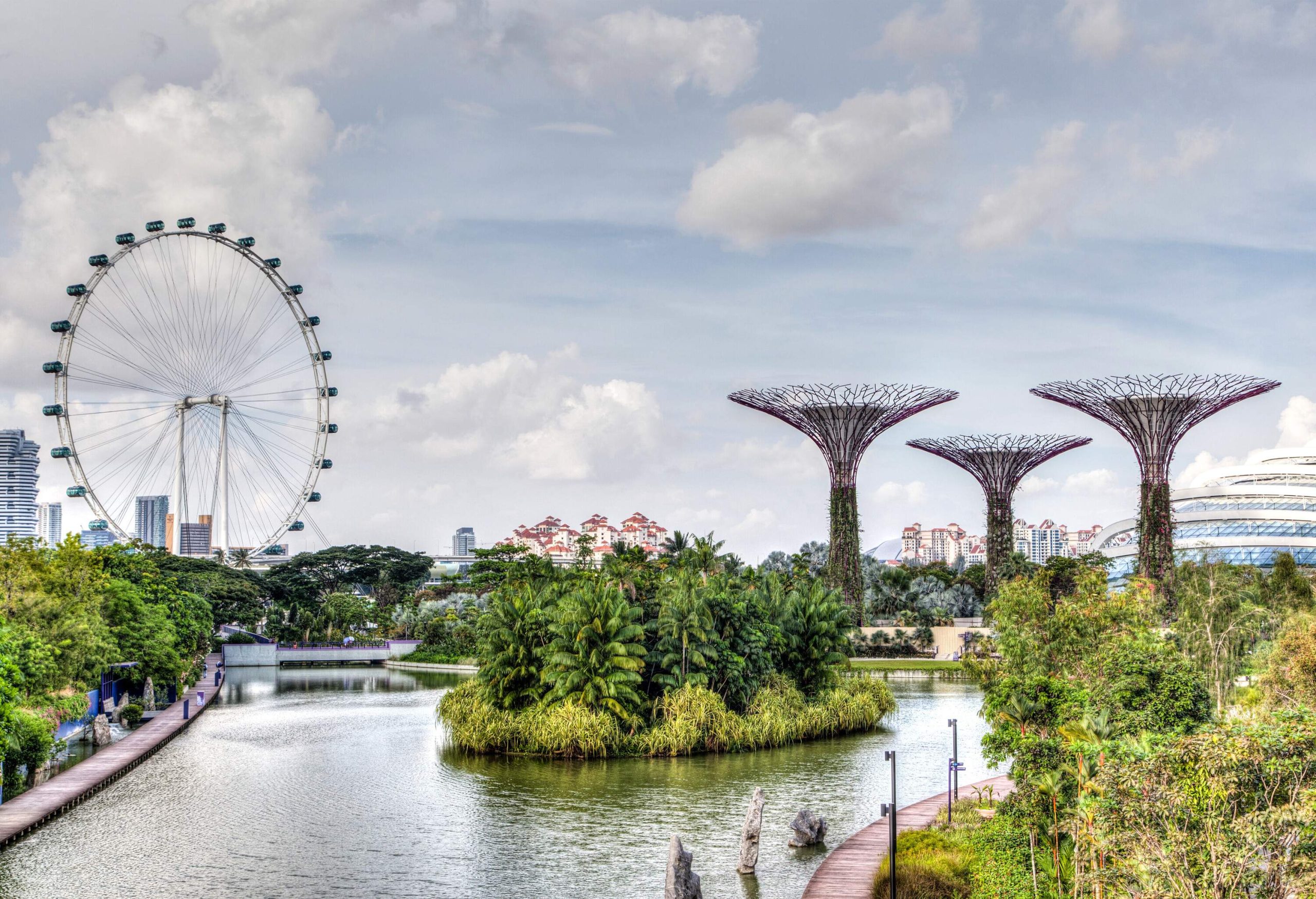 A Ferris wheel and a man-made vertical garden shaped like trees adorning the skyline by the bay.