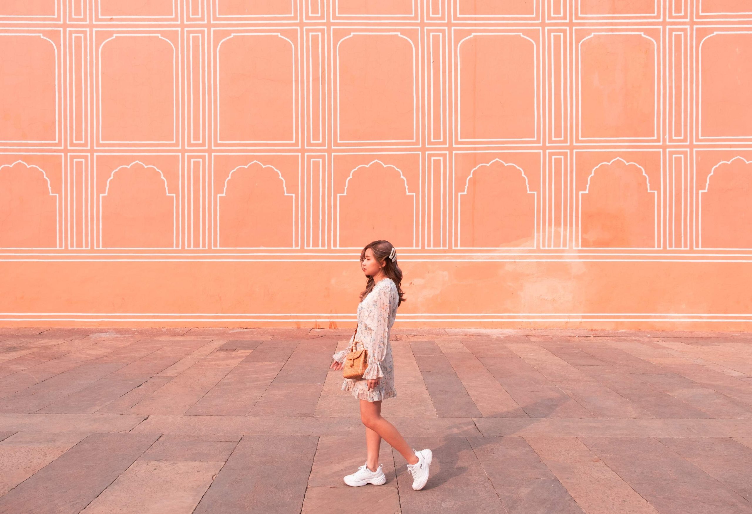 Young lady walk along Painted Pink Wall of Jaipur City Palace, Rajasthan, India