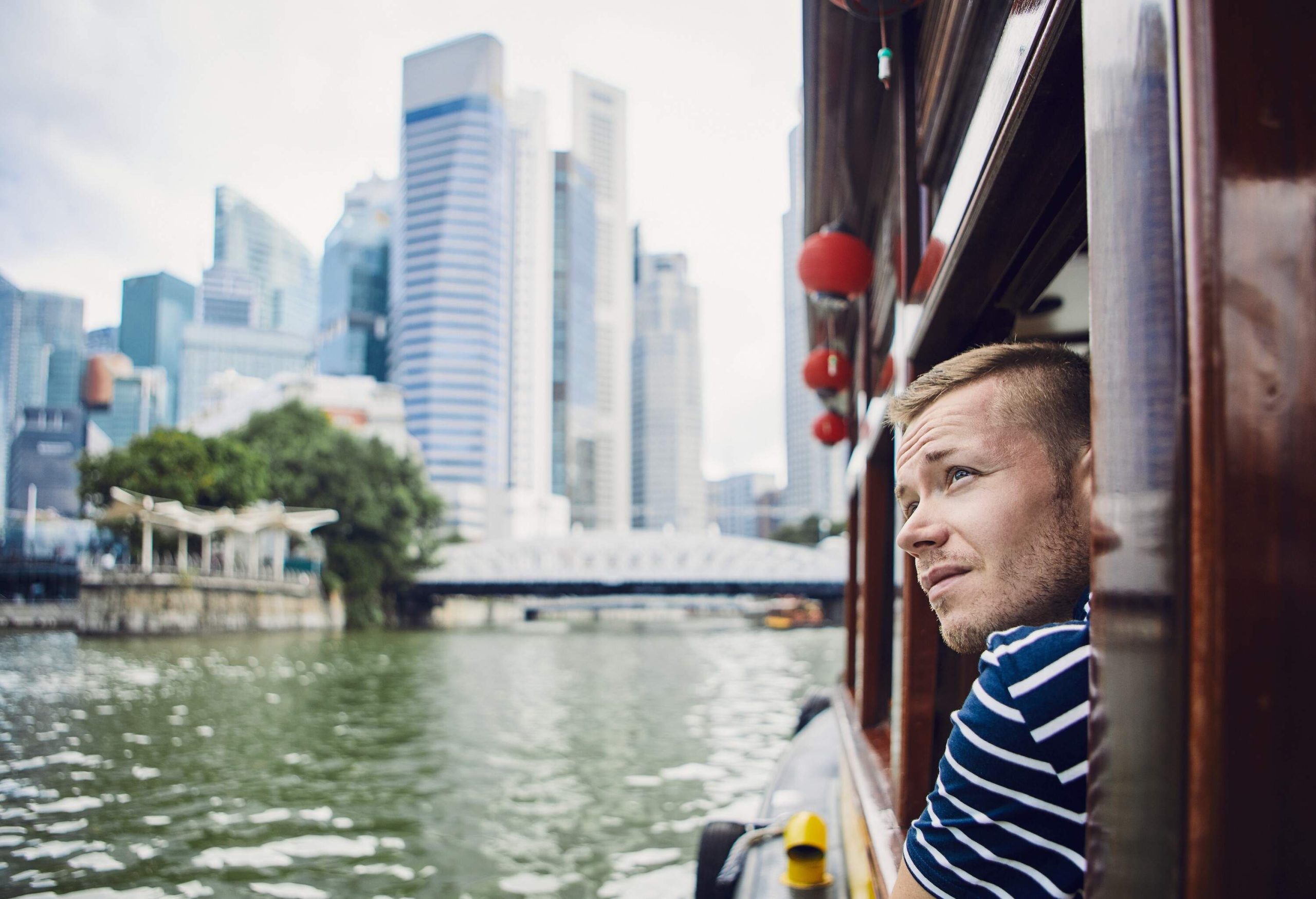 A curious person peeks through the window of a ferry, gazing in awe at the surrounding buildings that paint a vibrant tapestry of the cityscape.