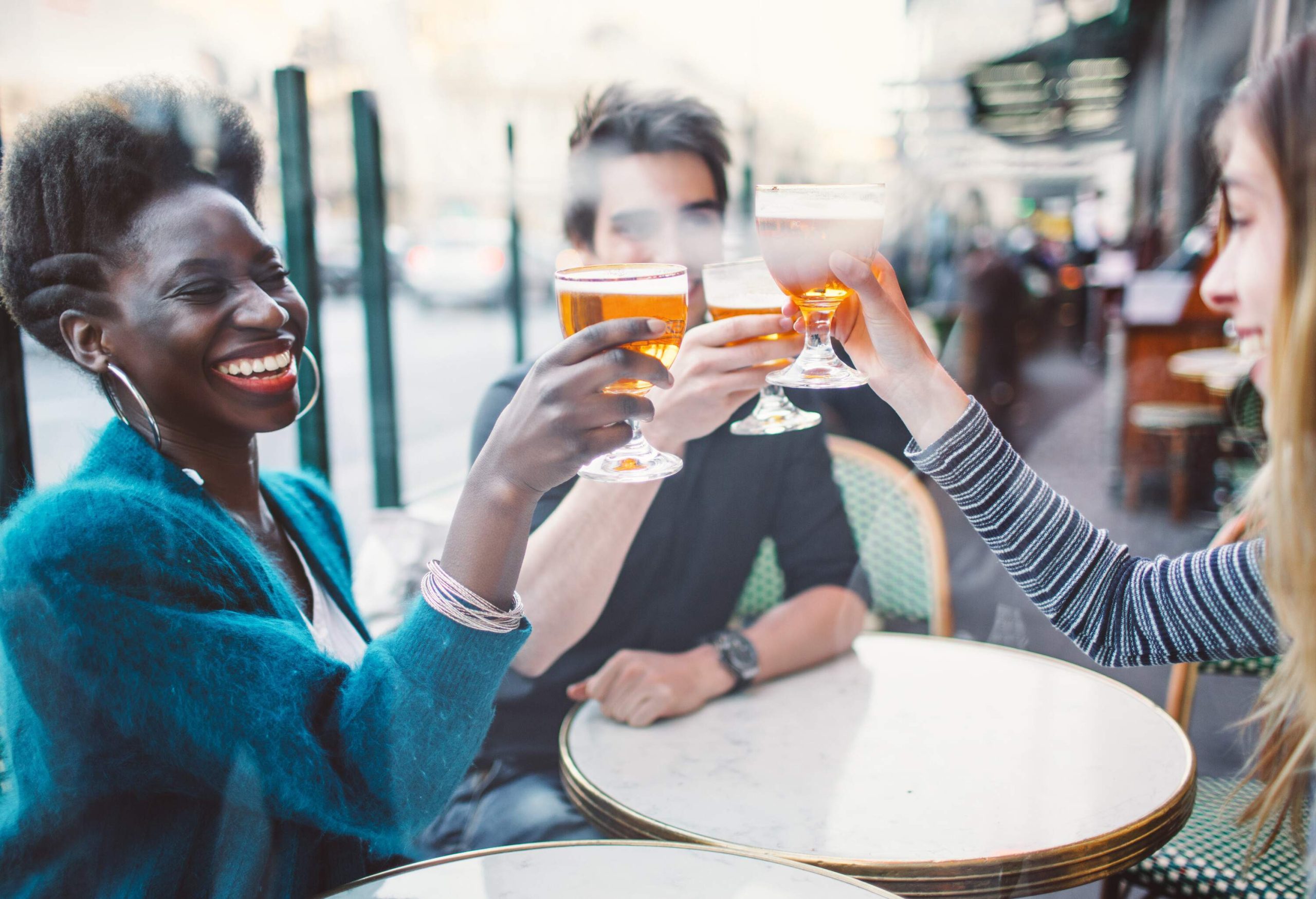 A circle of friends lifts their glass of beer in the air for a toast.