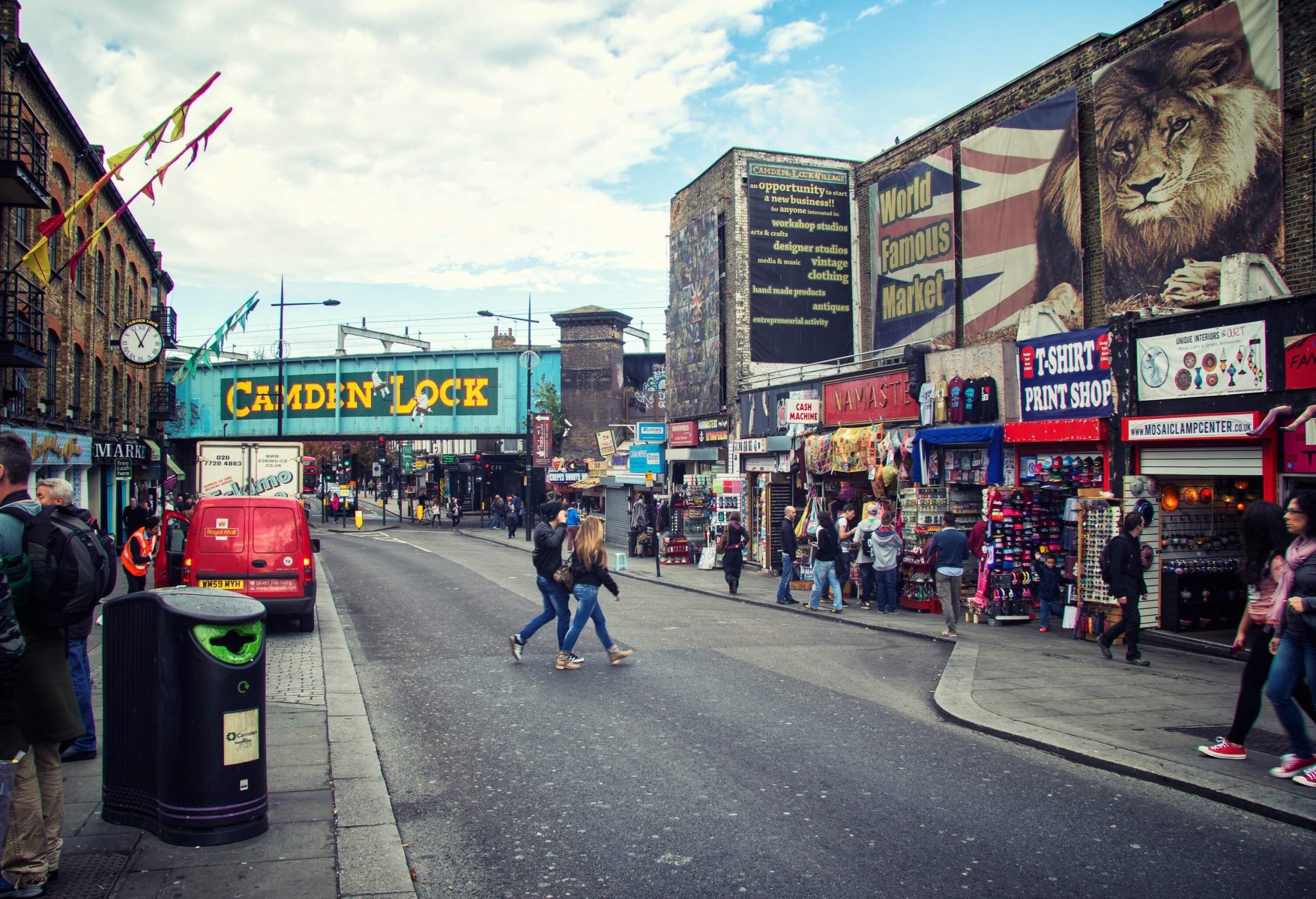 People strolling through the Camden High Street with colourful shop signs and banners.