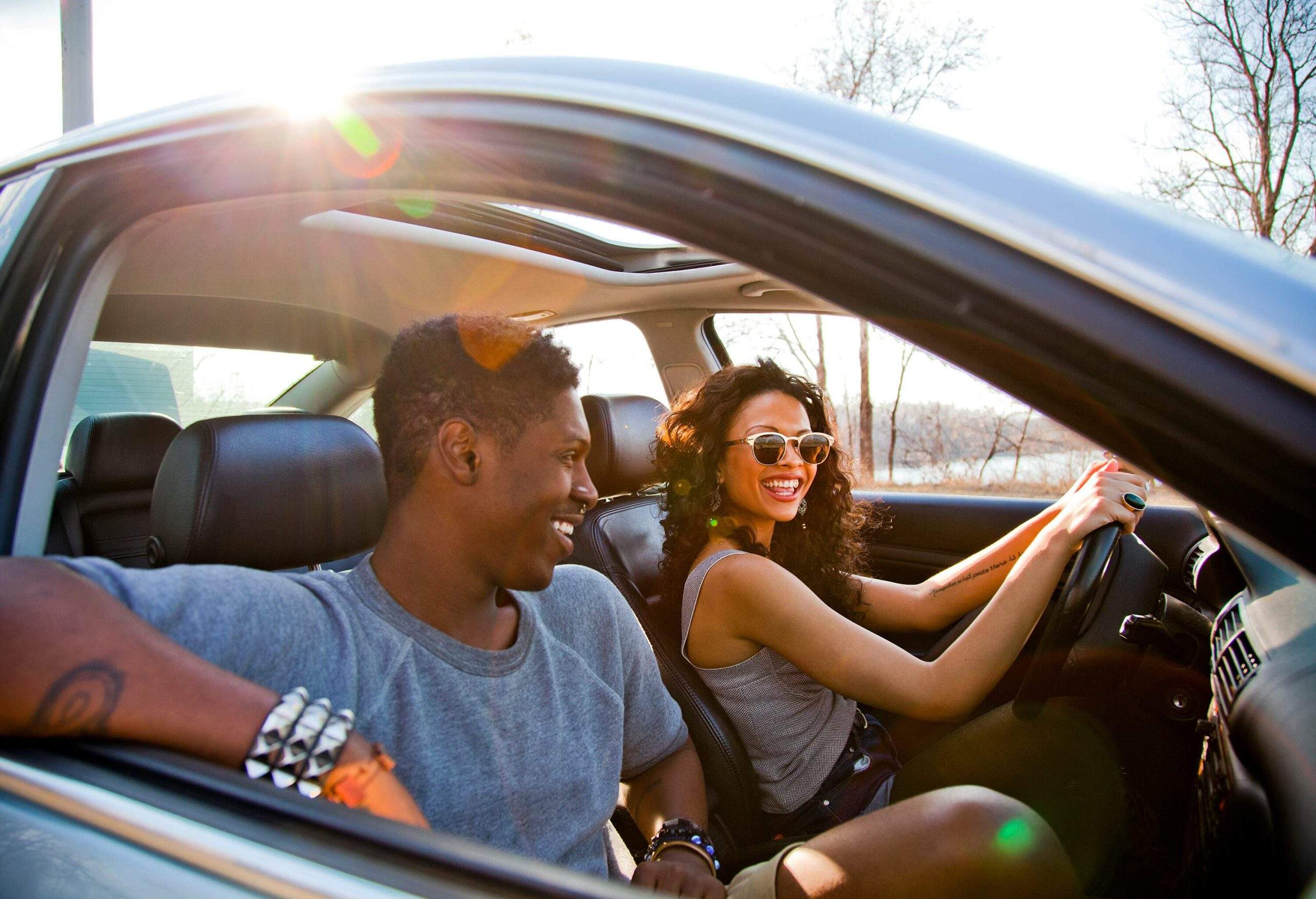 A woman behind the wheel of a car with a male passenger.