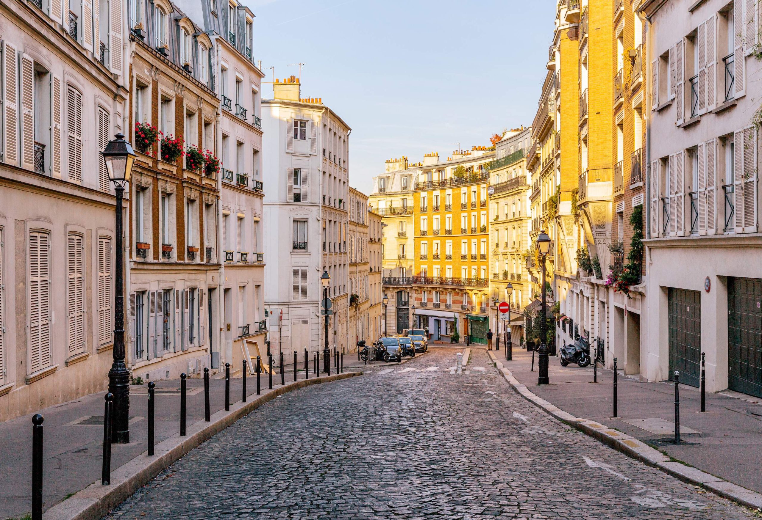 A cobblestone street lined with guard posts and lofty buildings.