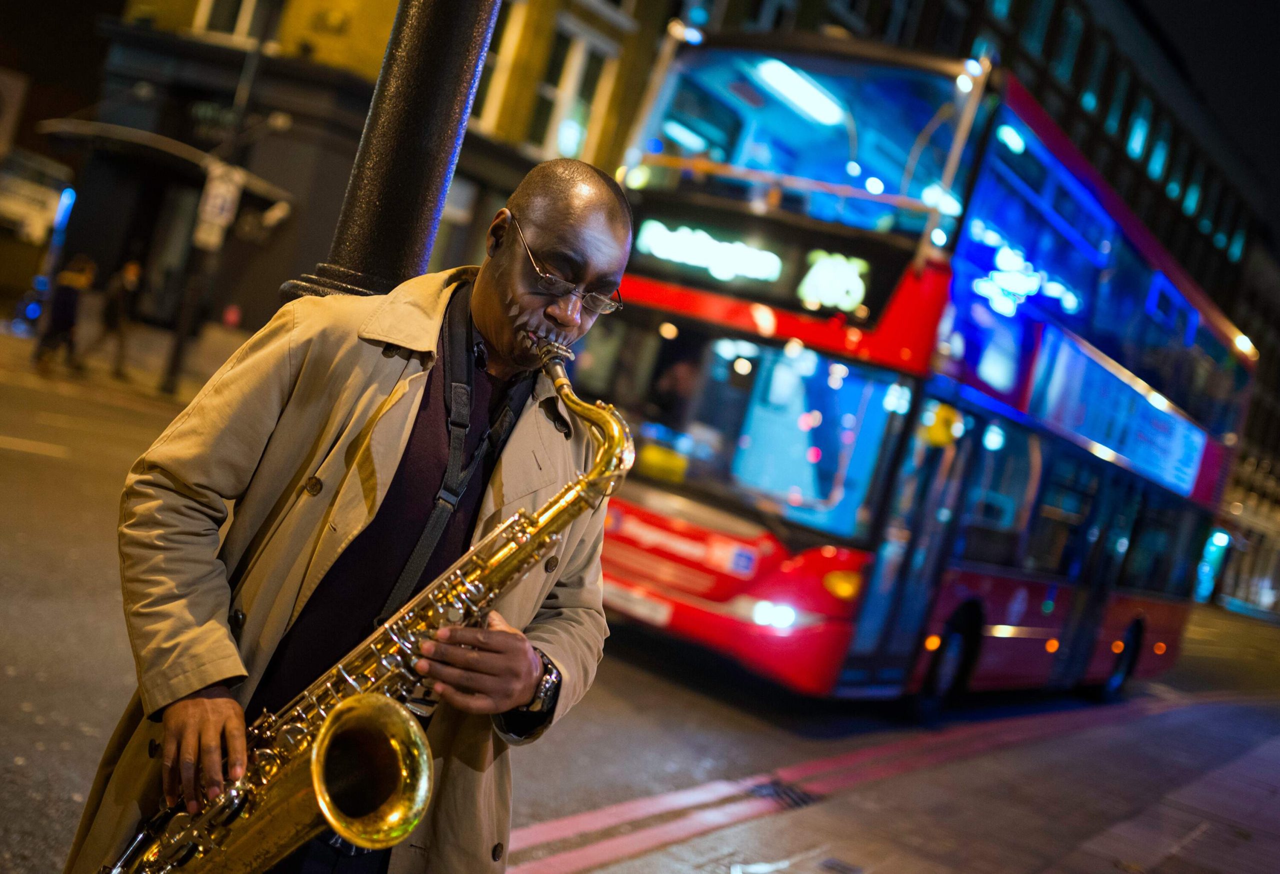 Black Street Musician in London, UK,  playing on saxophone in the evening,