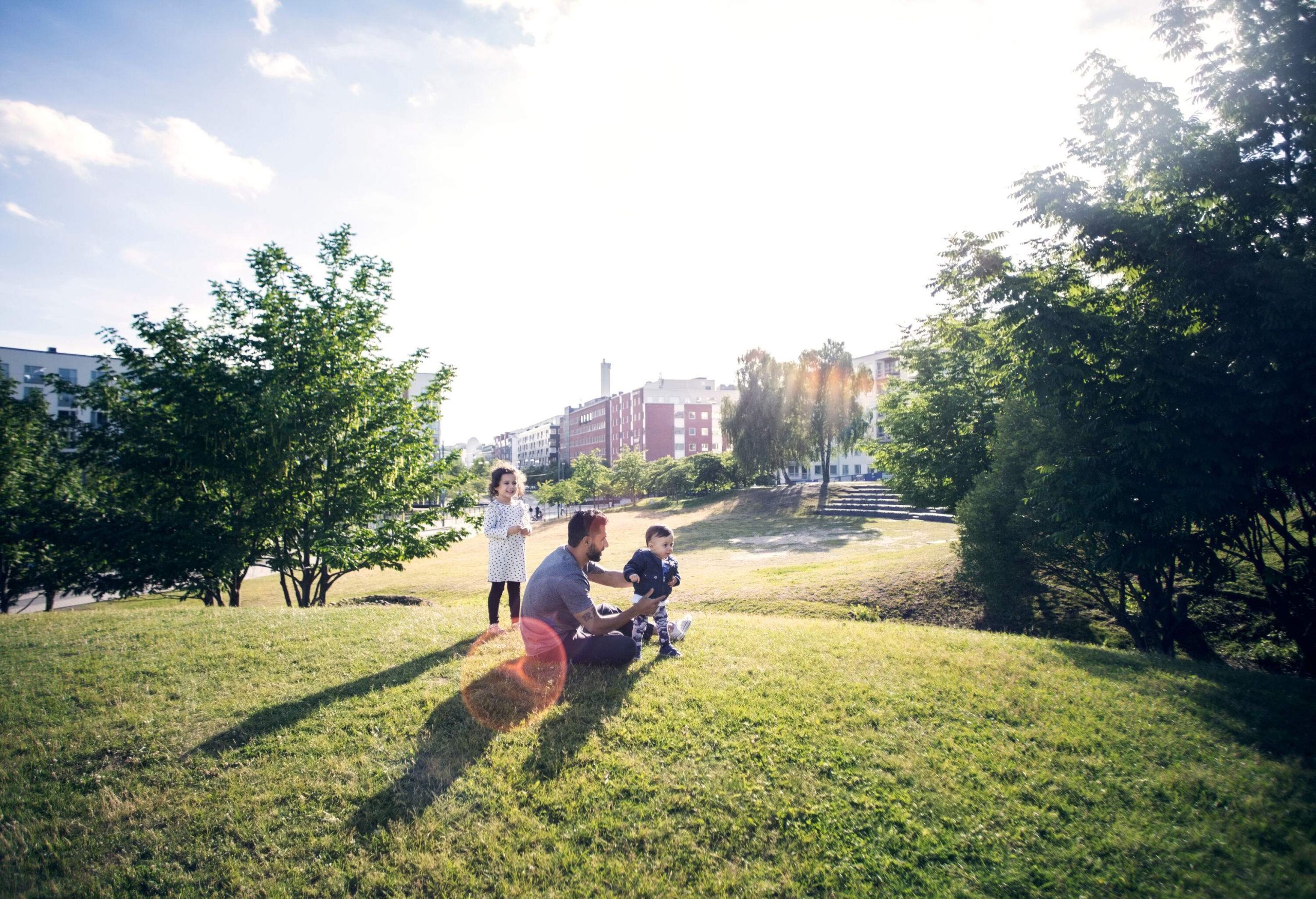 A man and two small children enjoying a sunny day in a park.