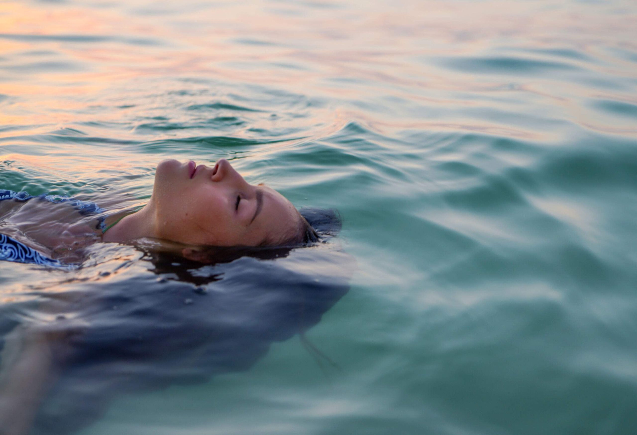 Relaxed woman floating in the water on the beach.