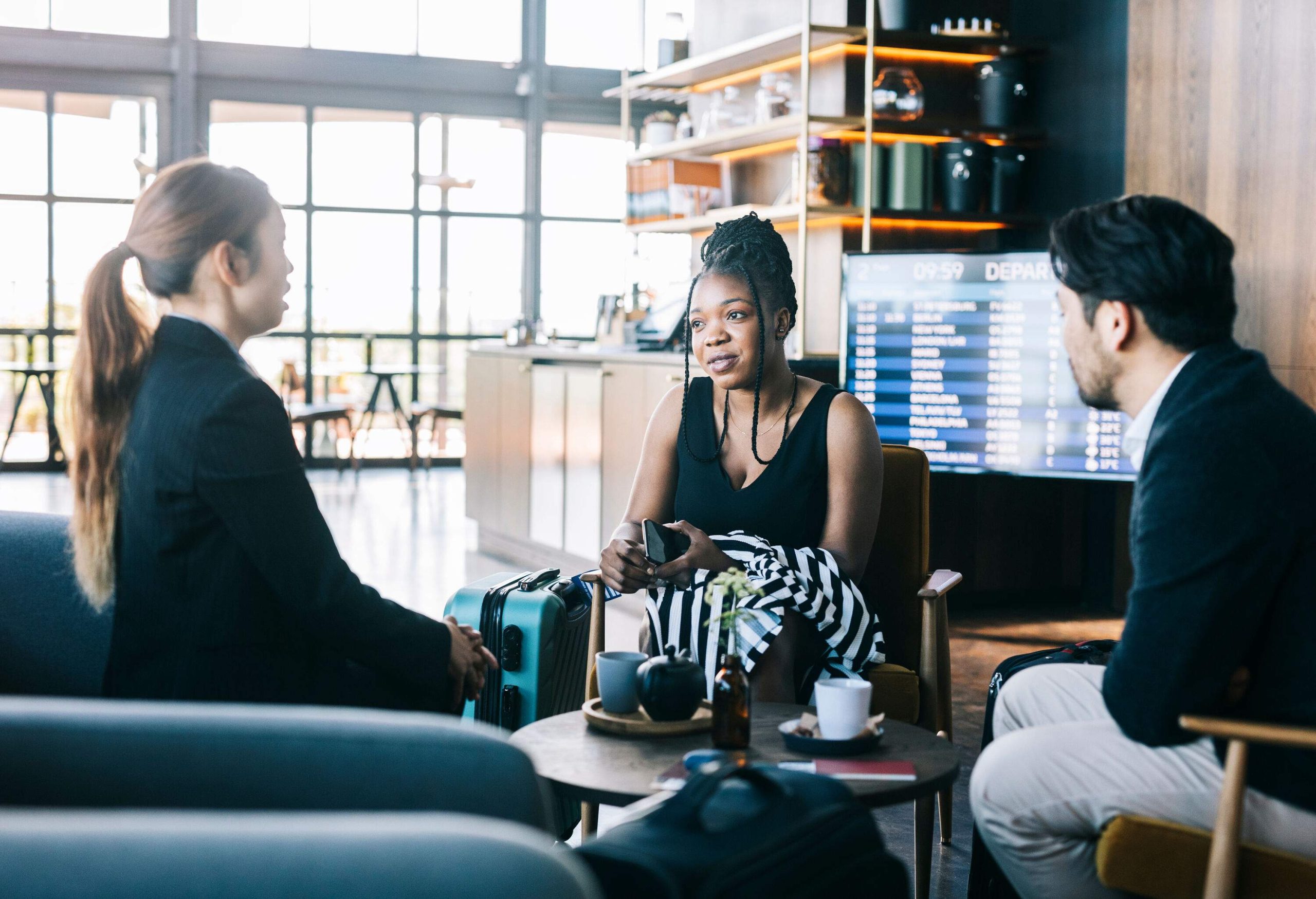 Three people in business casual attire chatting in a café.