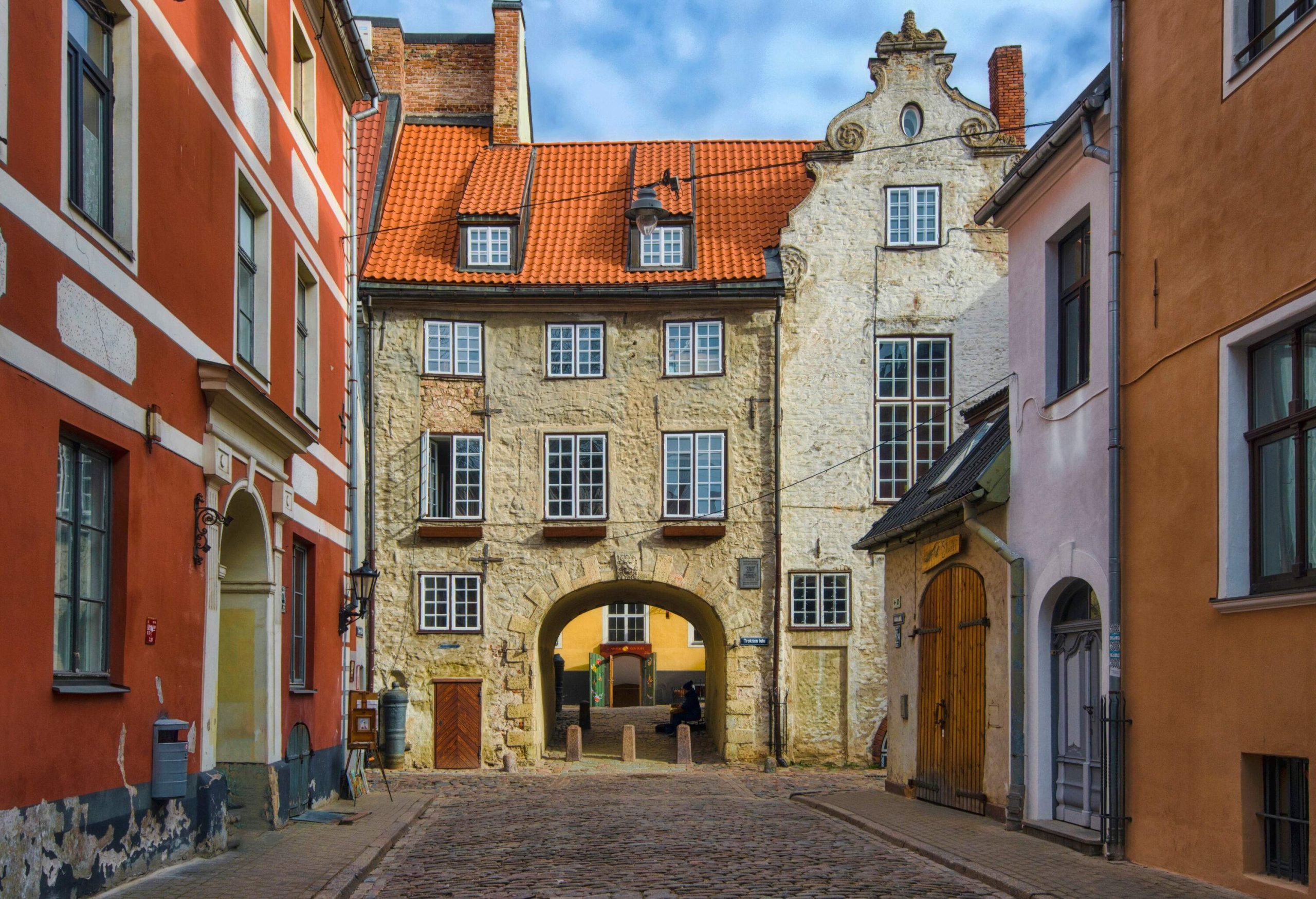 Historic buildings with arched doorways surrounding a cobblestone path in an old village.