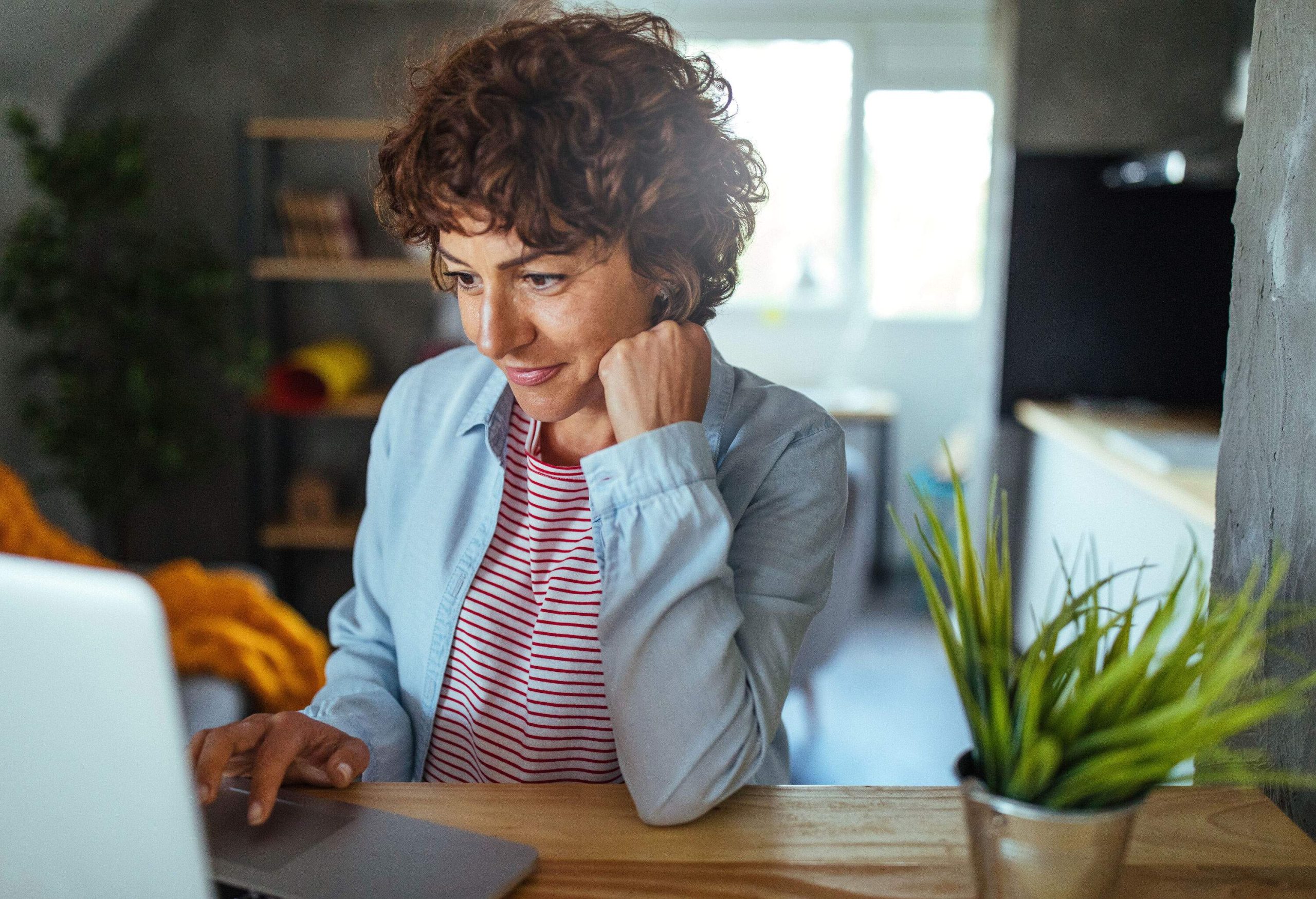 A woman focused on her laptop working from home.