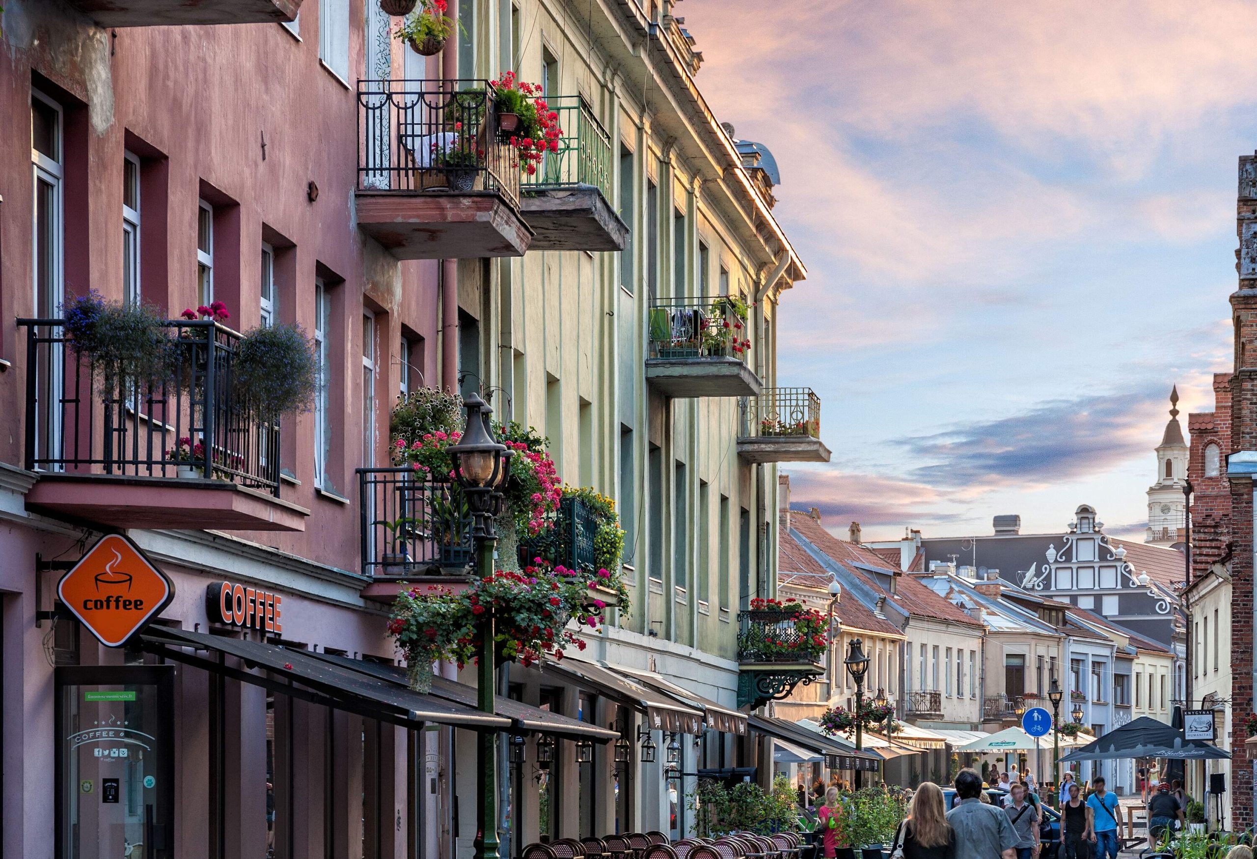 People leisurely wander along a picturesque cobblestone street, framed by buildings boasting charming balconies.