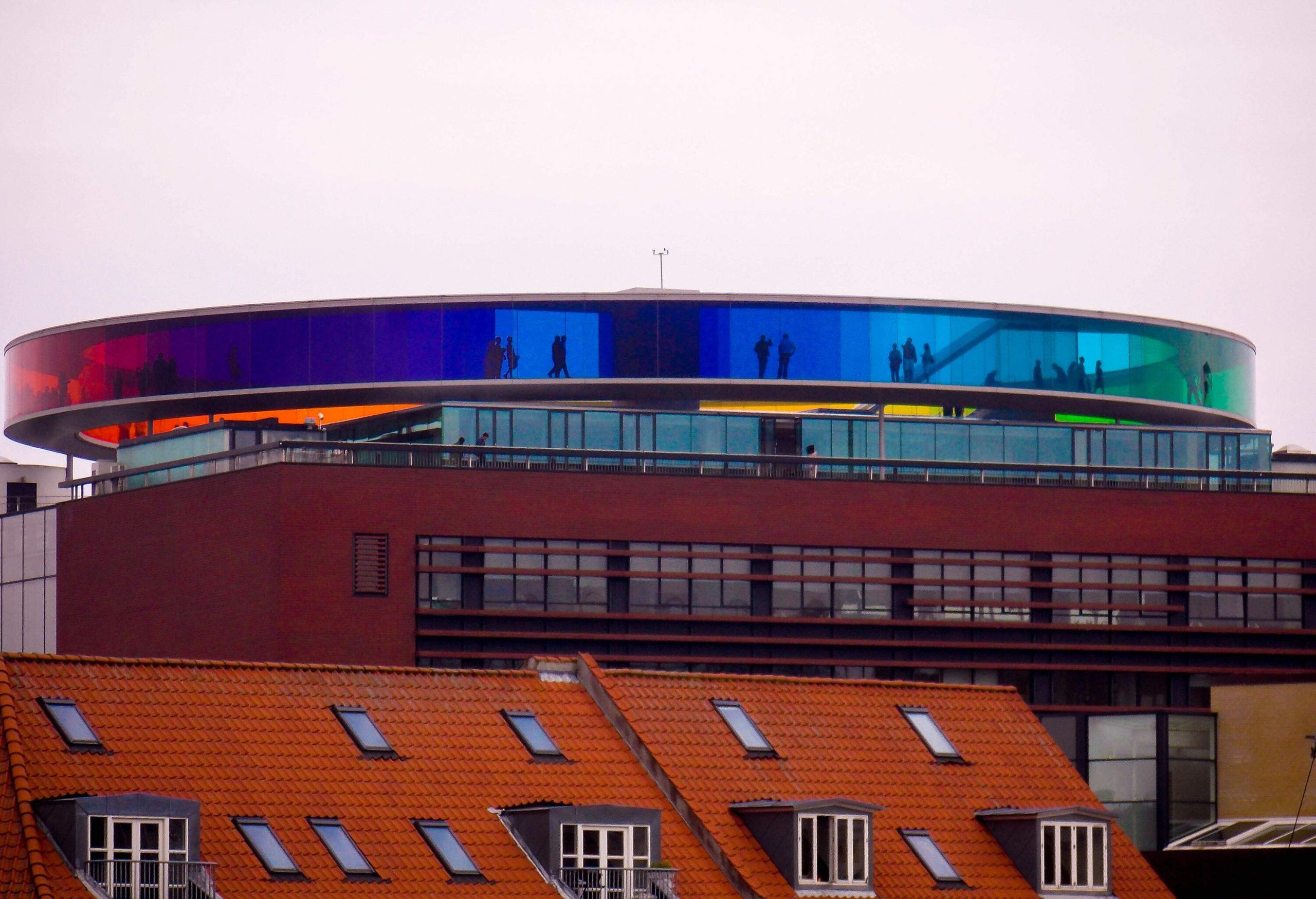 Silhouette of people walking along a rainbow-coloured circular skywalk.