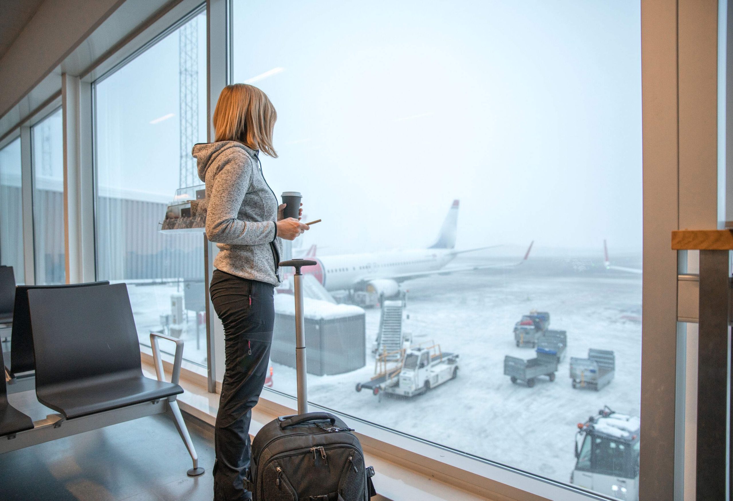 Woman standing close to window with luggage at airport