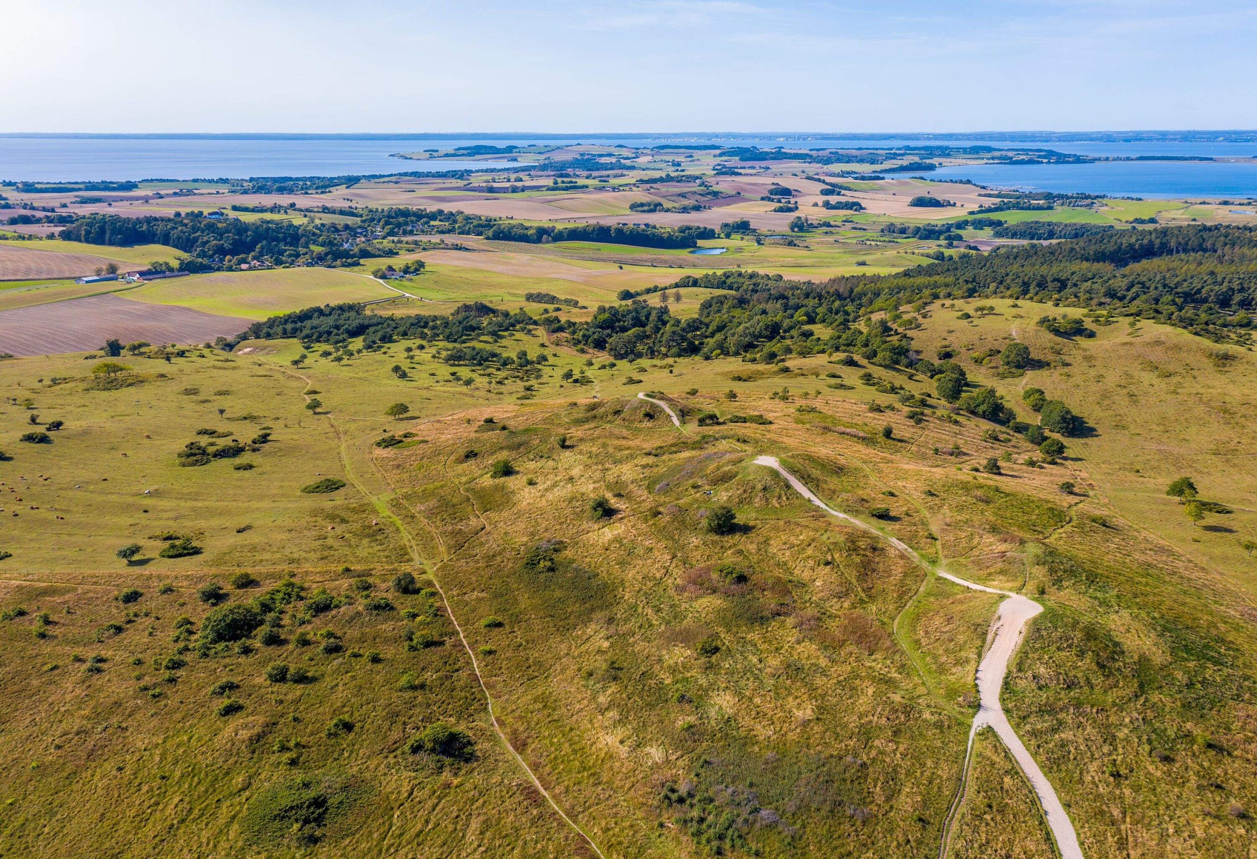 Mols Hills, Denmark - Trehøje seen from above. The three Bronze Age mounds of Trehøje, 127 metres above sea level, offer a panorama view from Aarhus to Ebeltoft, including four inlets: Kalø, Begtrup, Knebel and Ebeltoft. From up here you can see the National Park’s border to the south west, where fertile clay once deposited by the ice means the land is intensely farmed, as opposed to the nutrient-poor sand left by the ice on the hills and on the coastline along Ebeltoft Vig.