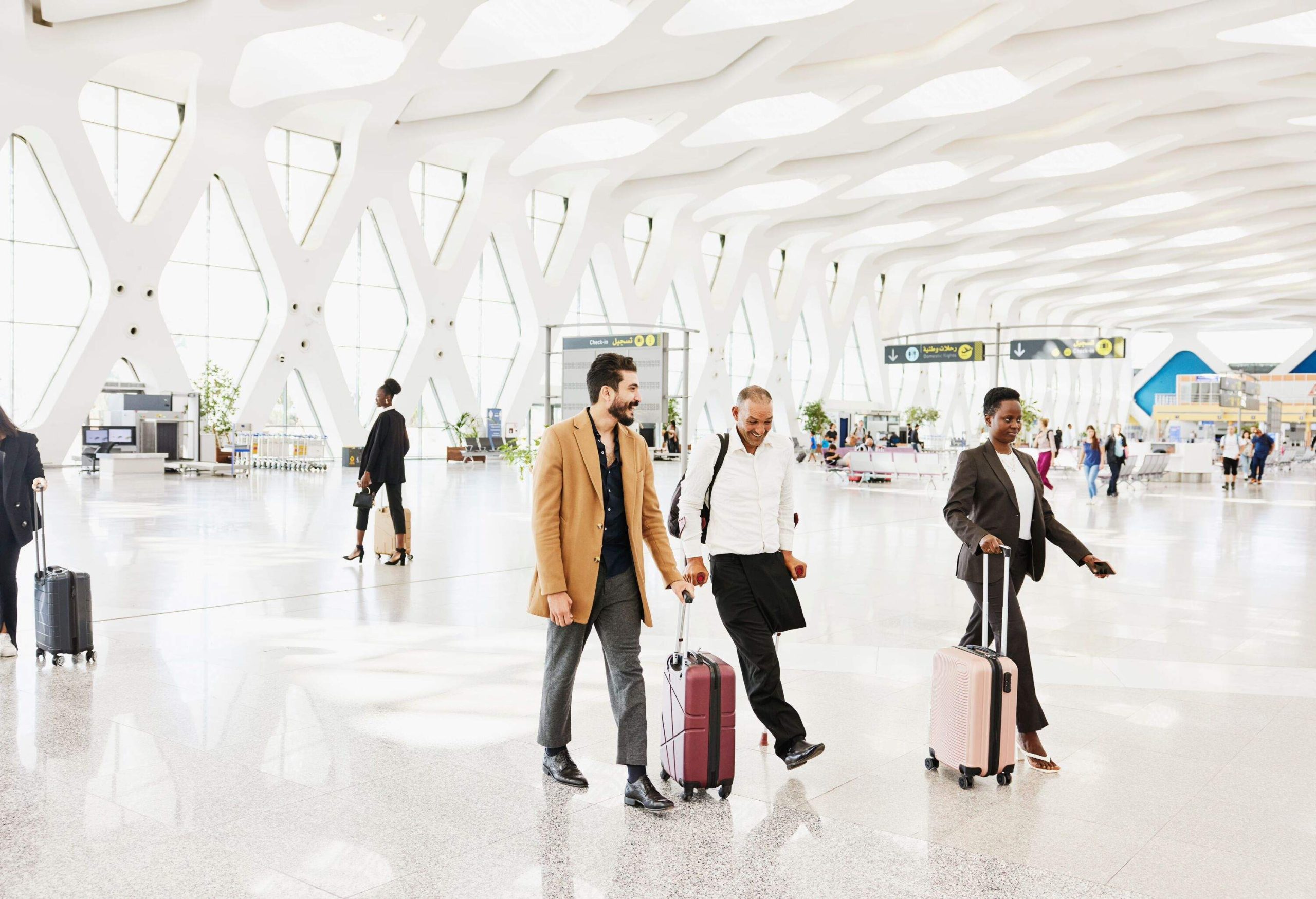 Wide shot of disabled traveler walking through airport terminal with friend before catching flight