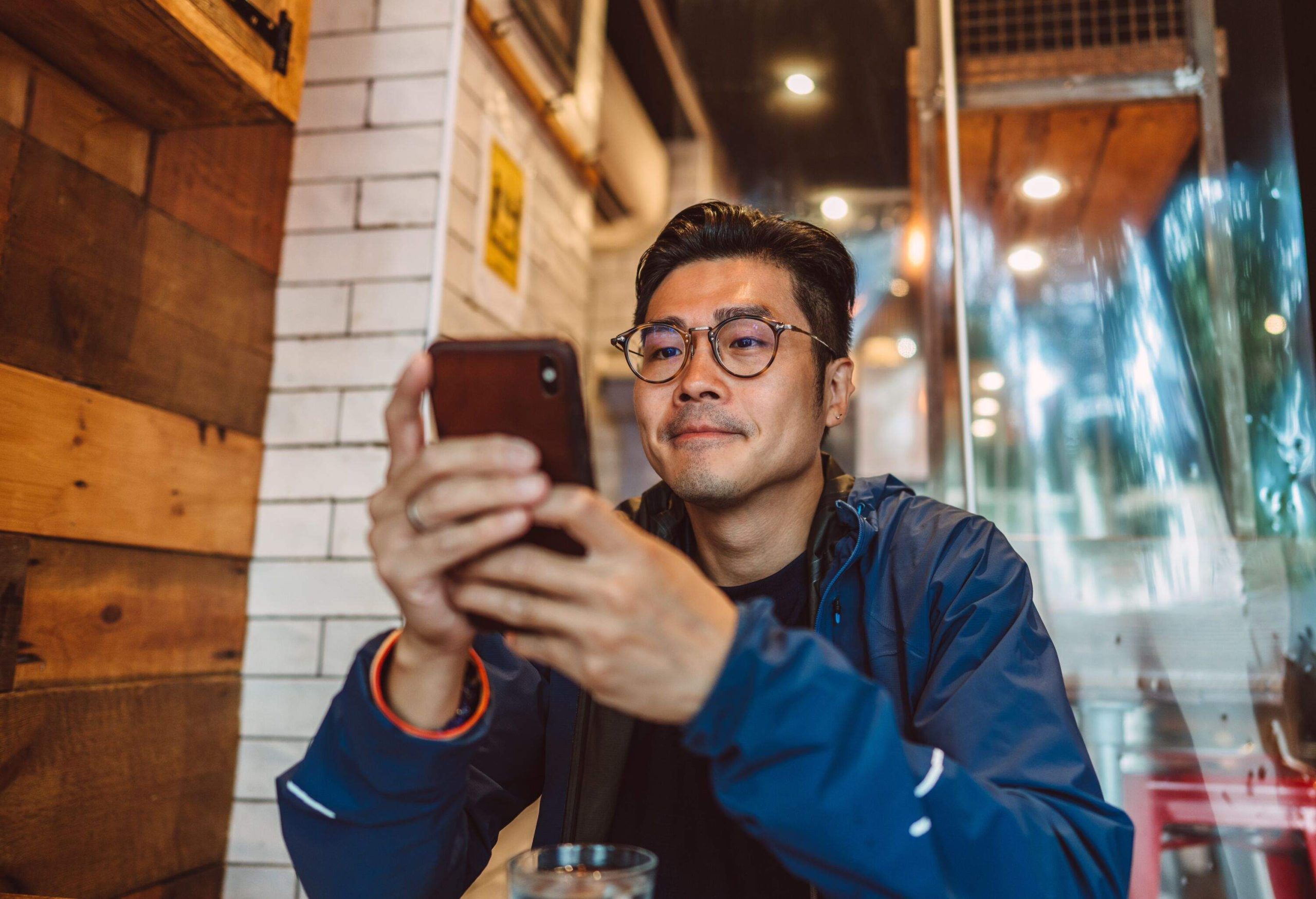 Asian man making order from the digital menu on smartphone in restaurant.