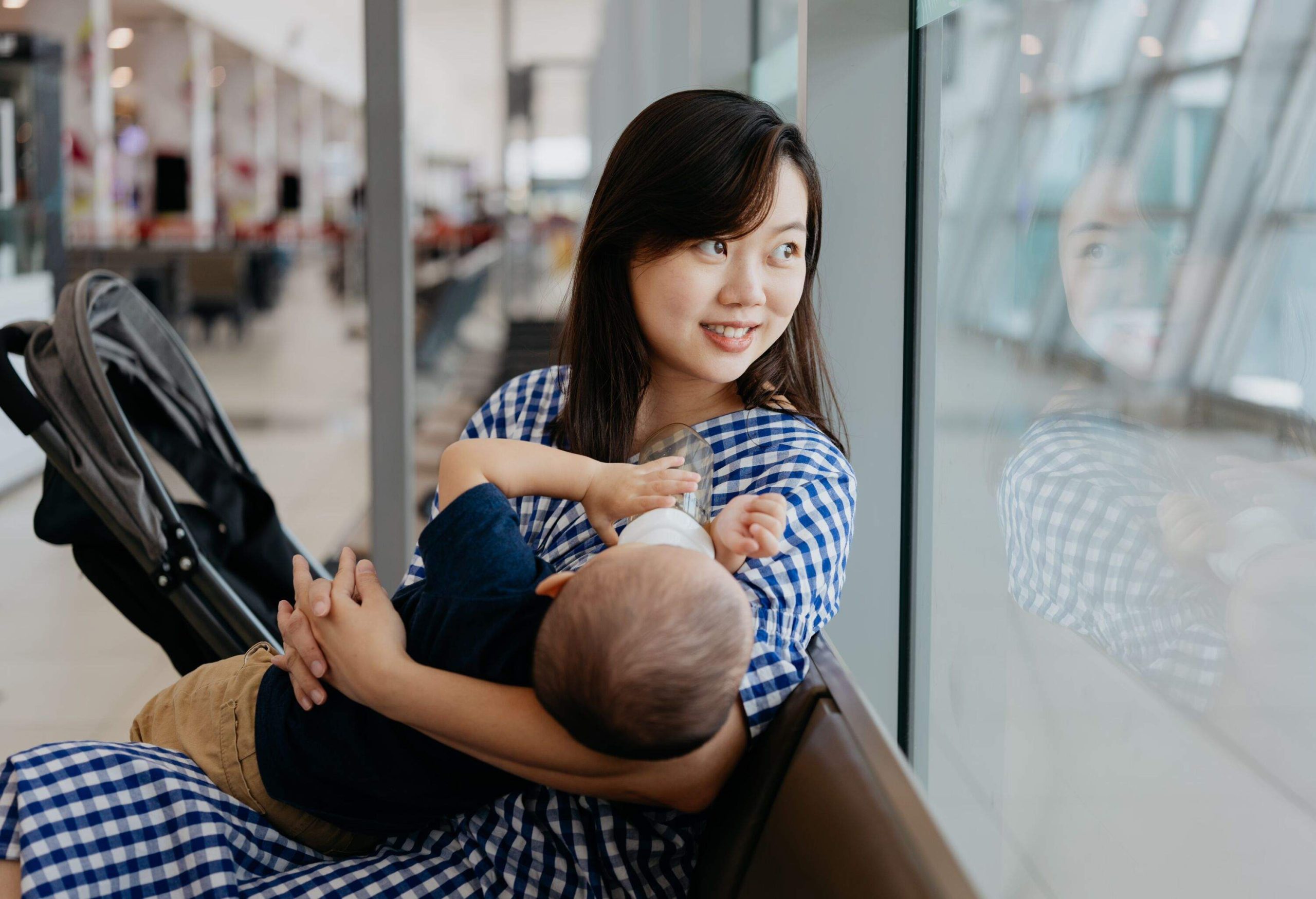 An woman feeding her baby while waiting for flight at the airport